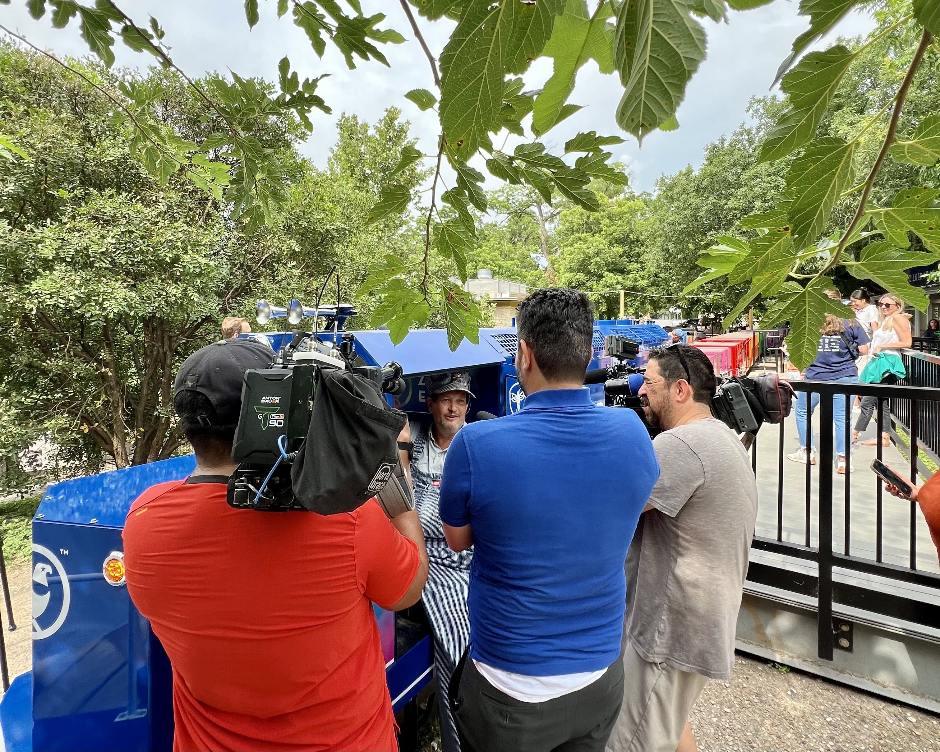 A photo of the train's engineer in the background with reporters crowded around him in the foreground.