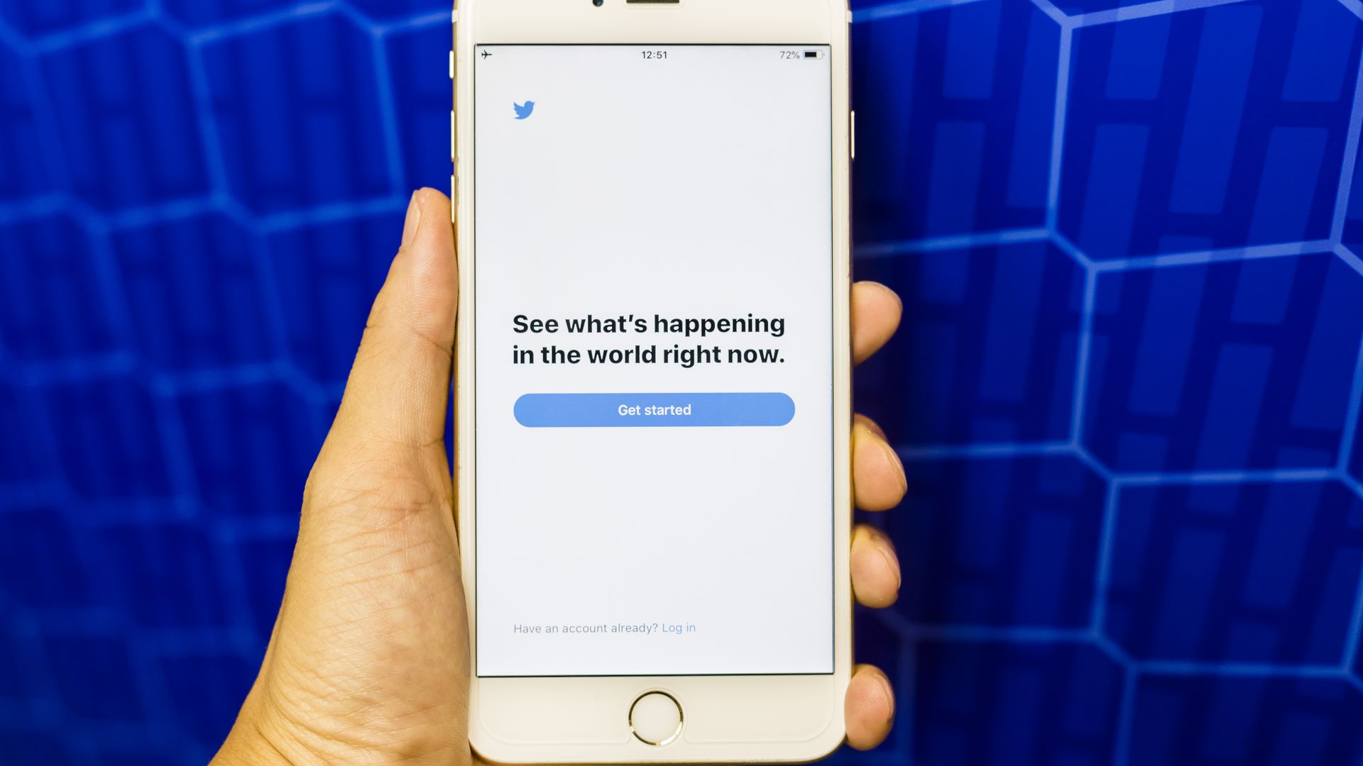 A hand holding a white iPhone with the Twitter app open 