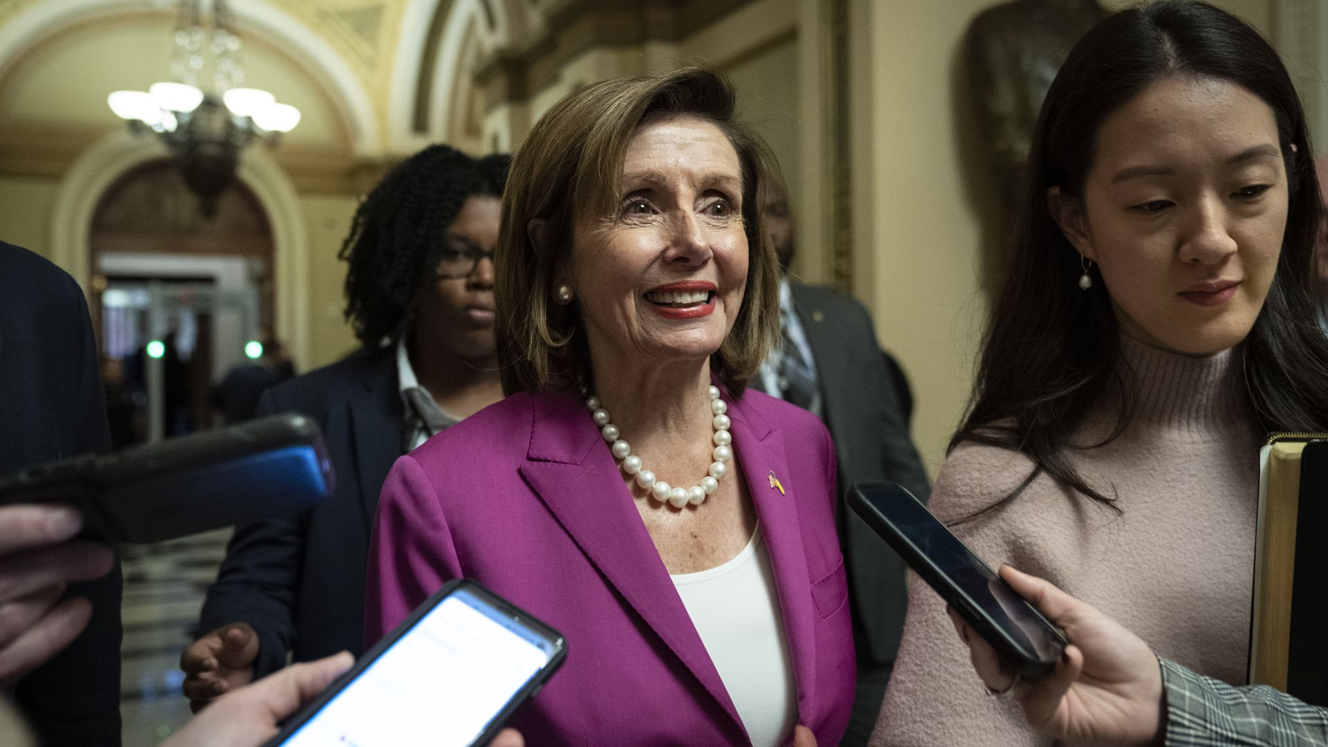 House Speaker Nancy Pelosi, wearing a magenta jacket, white shirt and pearl necklace, speaks to reporters at the Capitol.