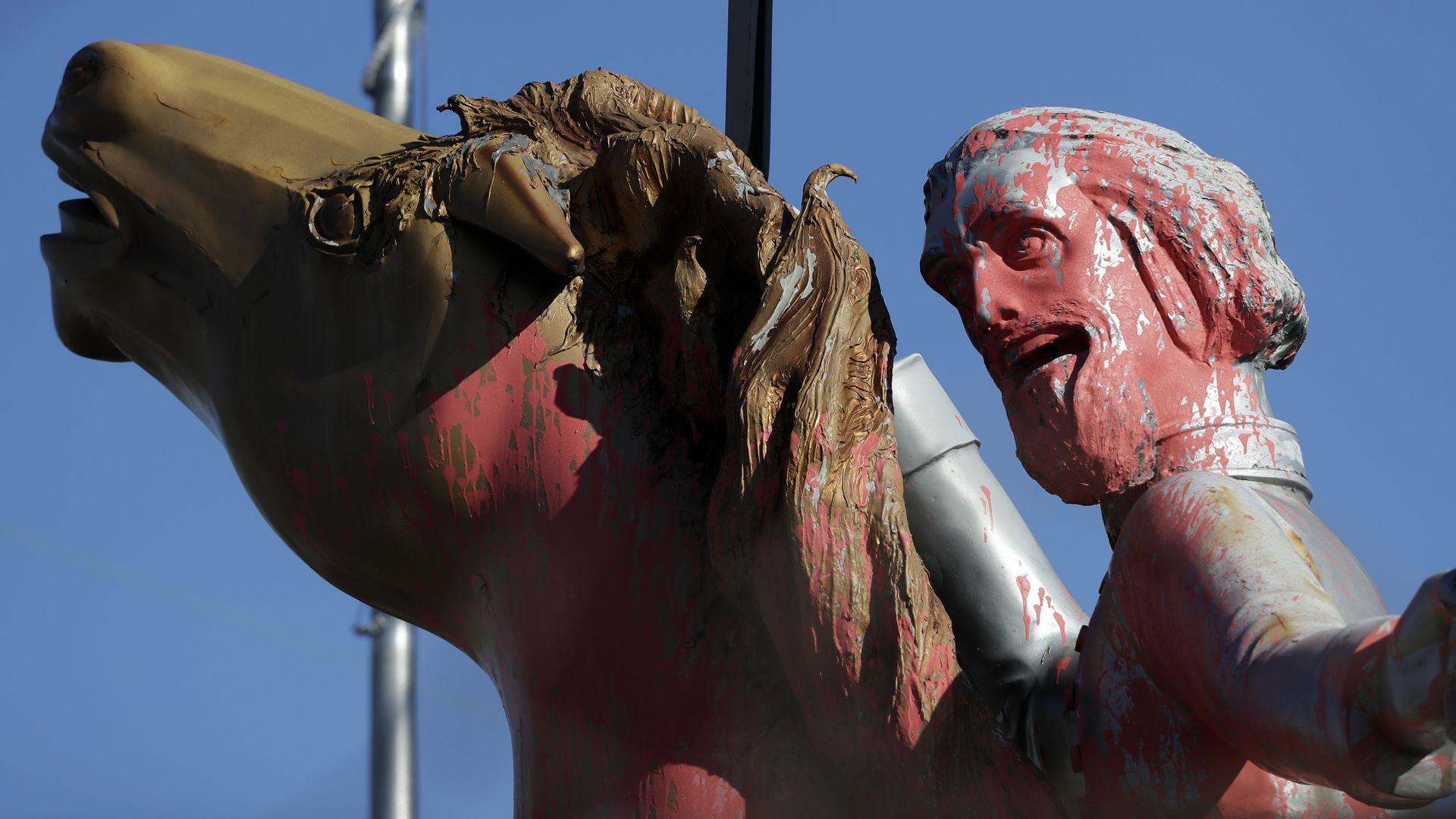 A statue of Nathan Bedford Forrest grinning and riding a horse is splattered with pink paint