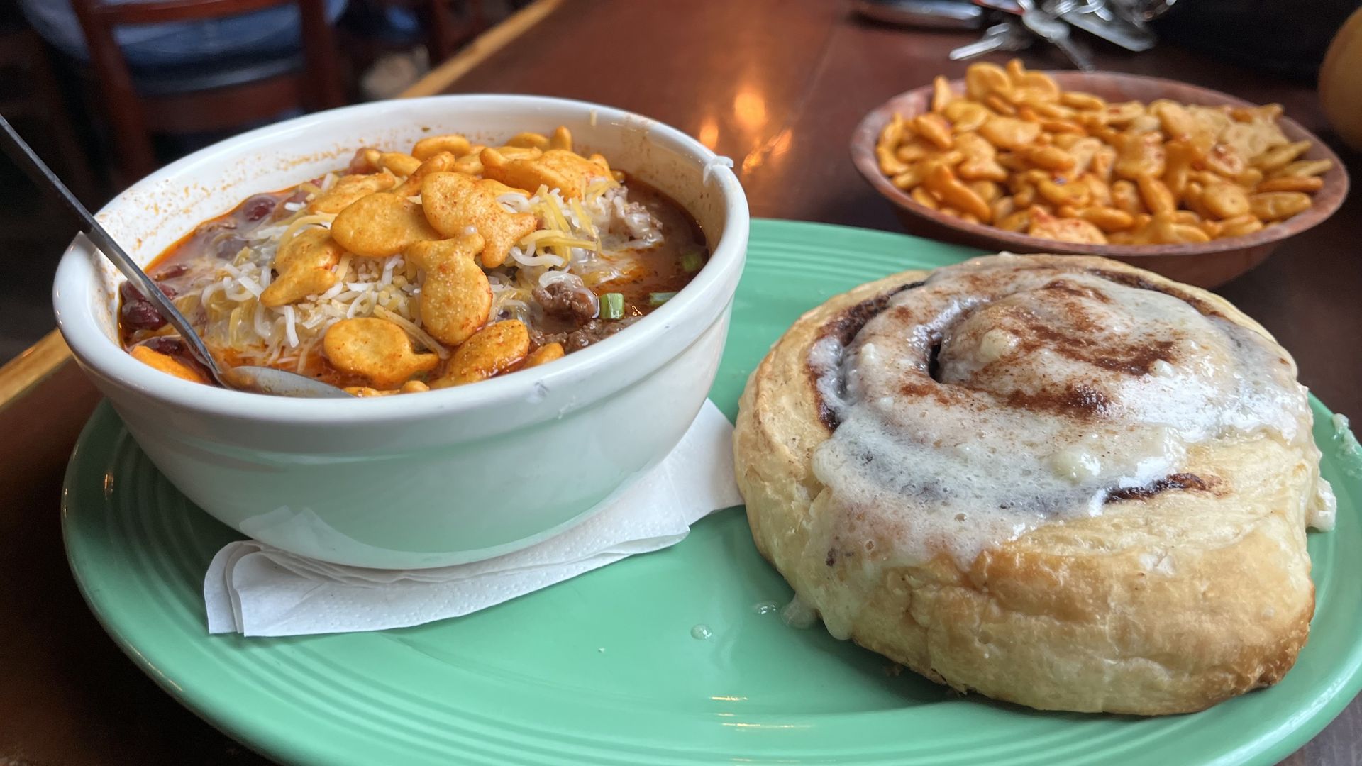 a bowl of chili with goldfish and a cinnamon roll