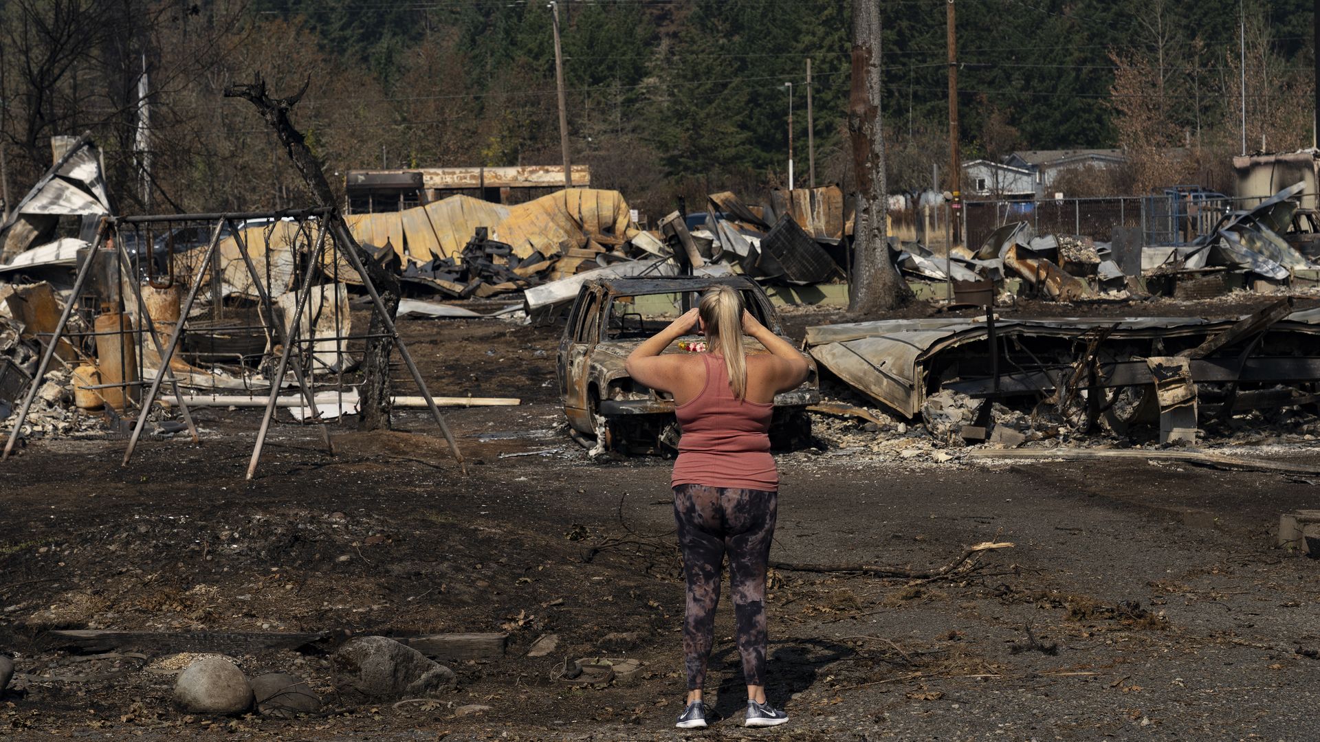 A person stands facing a large section of large burned by wildfires.