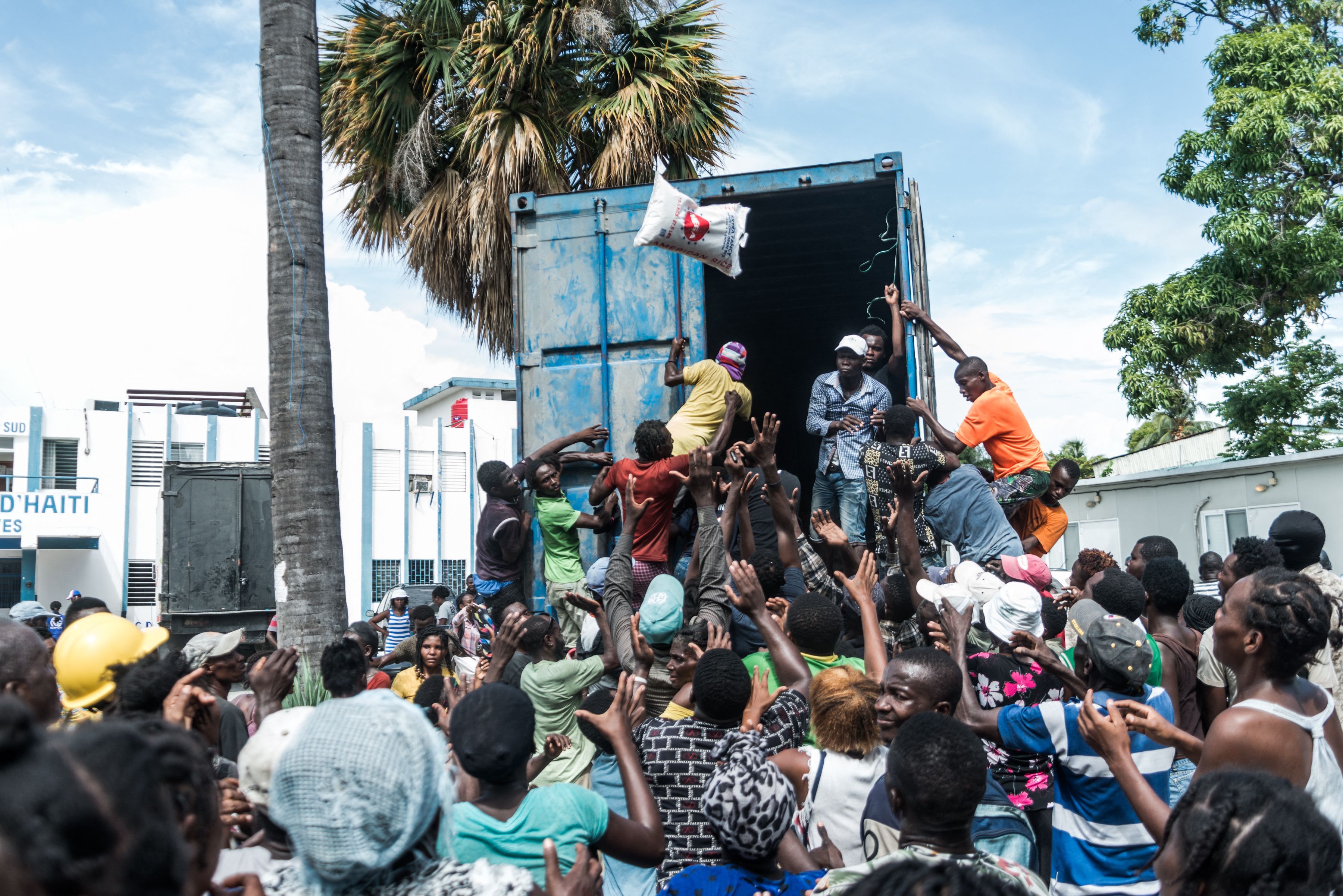 A man throws a bag of rice into a crowd of earthquake victims gathered for the distribution of food and water at Les Cayes, Haiti, on Aug. 20. 