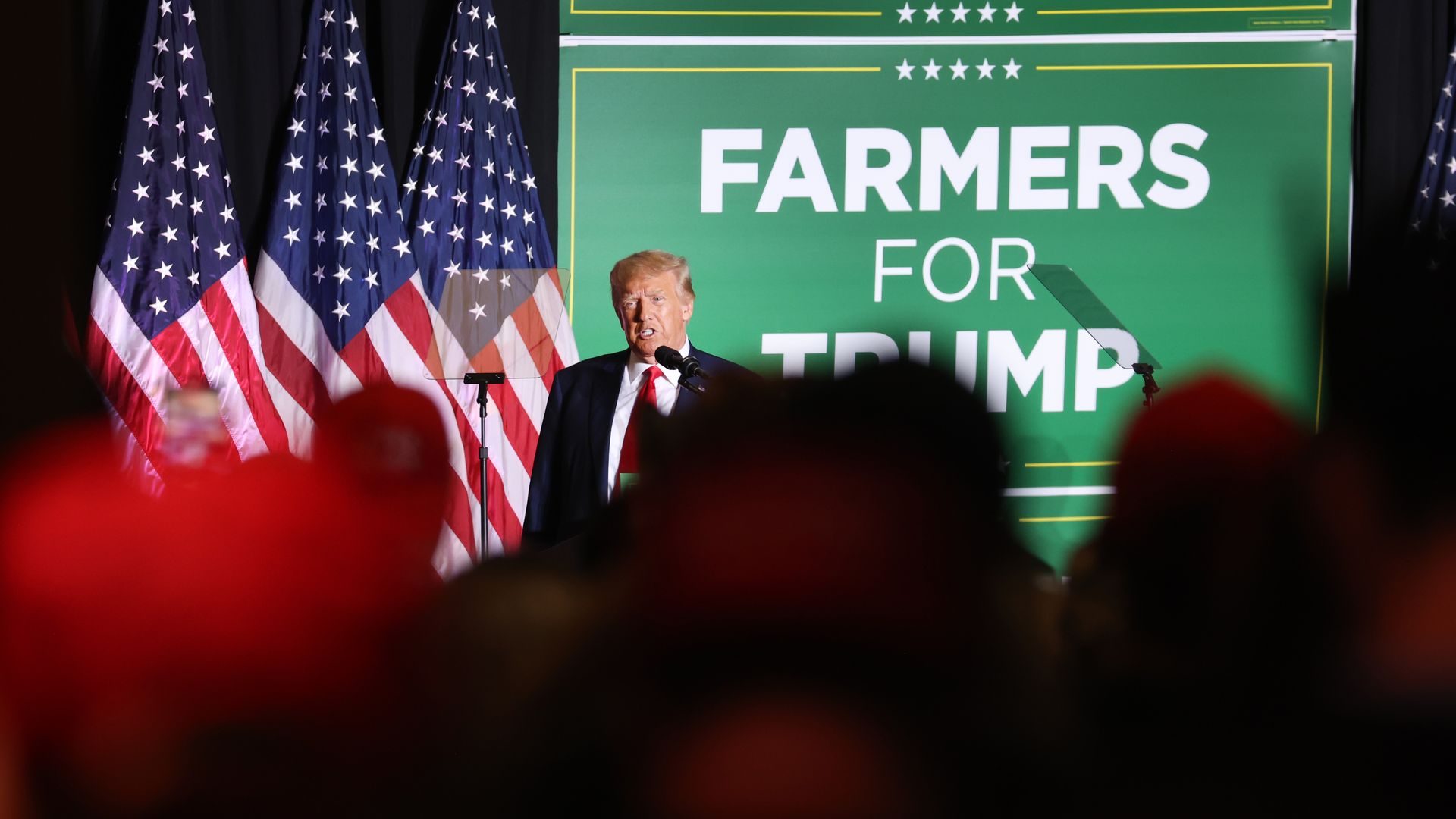 Donald Trump standing in front of a Farmers for Trump sign. 