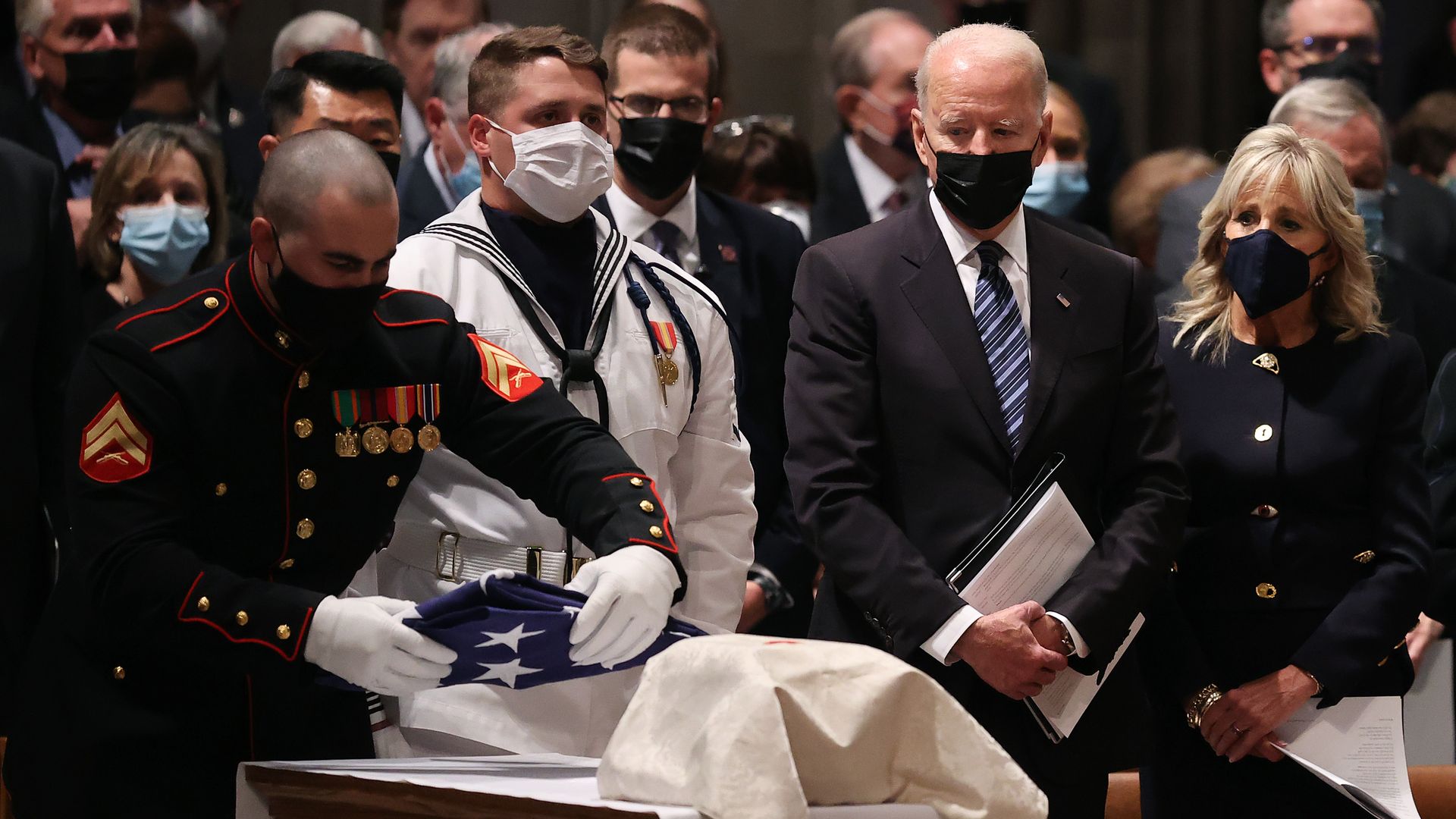 President Biden is seen watching as a Marine places a flag next to the urn bearing the ashes of the late Sen. John Warner.
