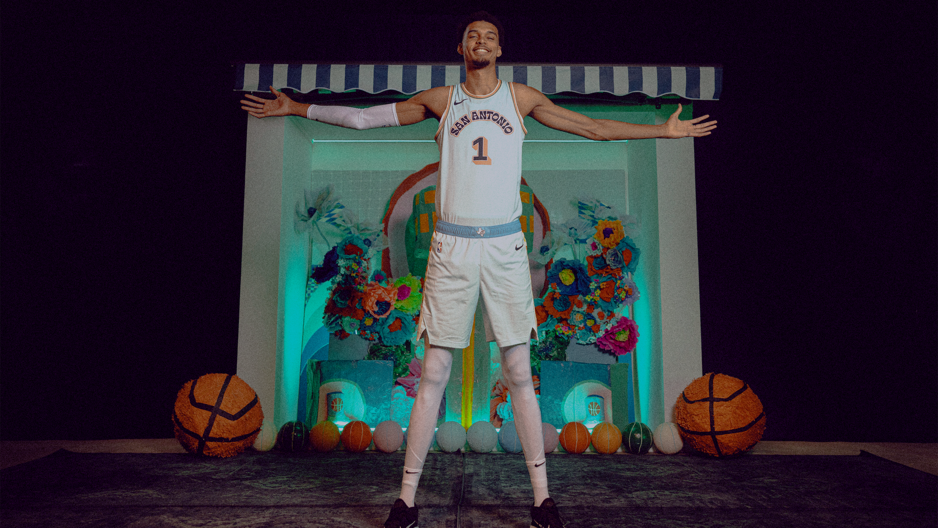 Victor Wembanyama stands with his arms outstretched.