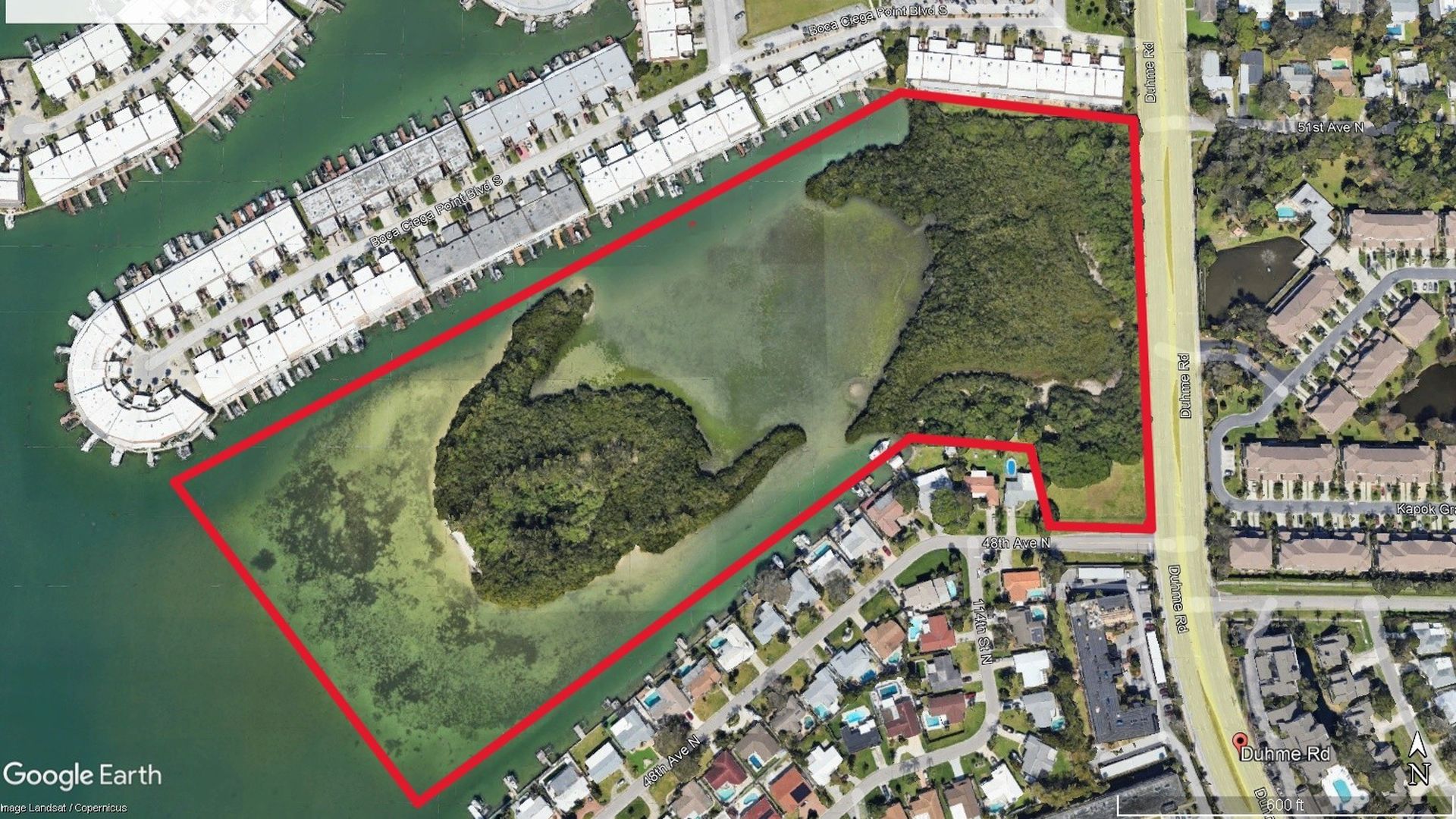 Satellite view of a red-outlined, irregular land parcel labeled "Duhme Road Reserve" along a canal, with dense trees, water, and nearby neighborhoods and a marina.