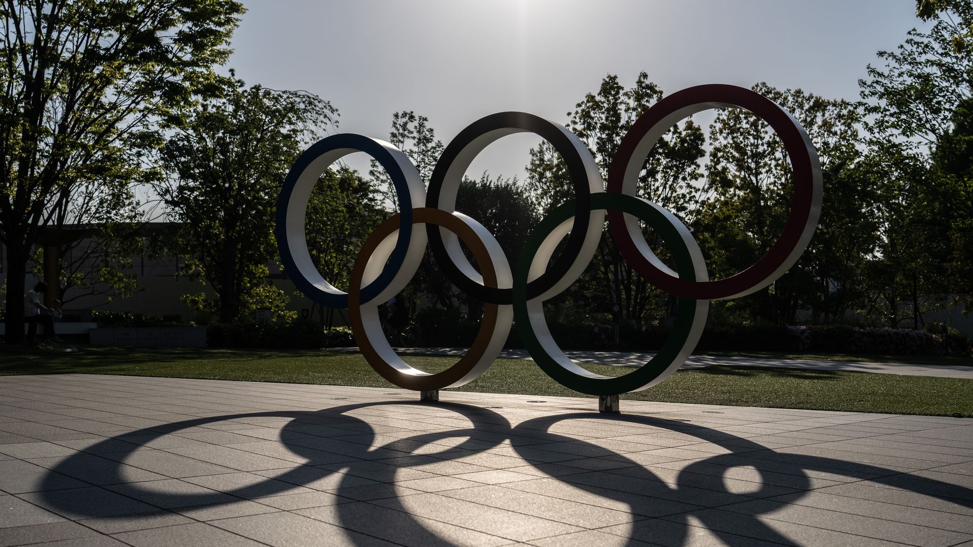 A shadow is cast as the sun sets behind the Olympic Rings in Tokyo, Japan.