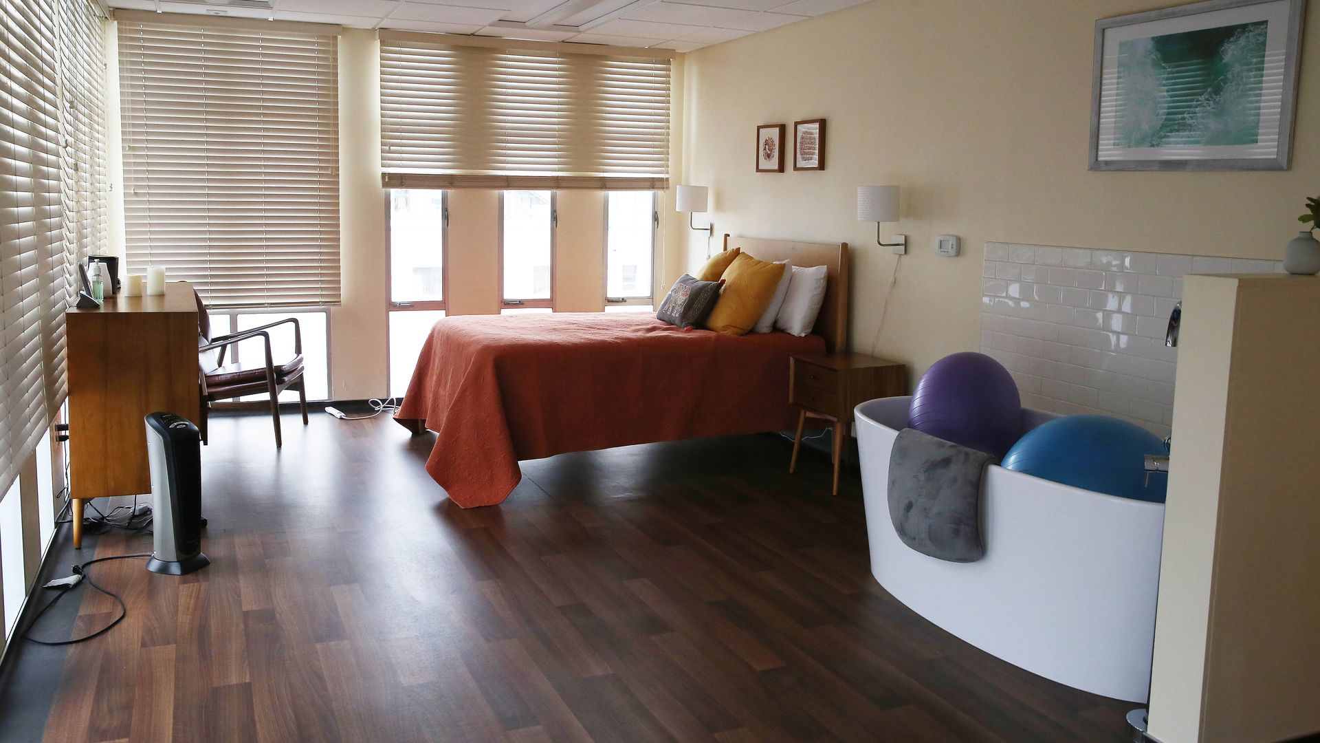 Photo of a room with an orange bed and a bathtub next to it