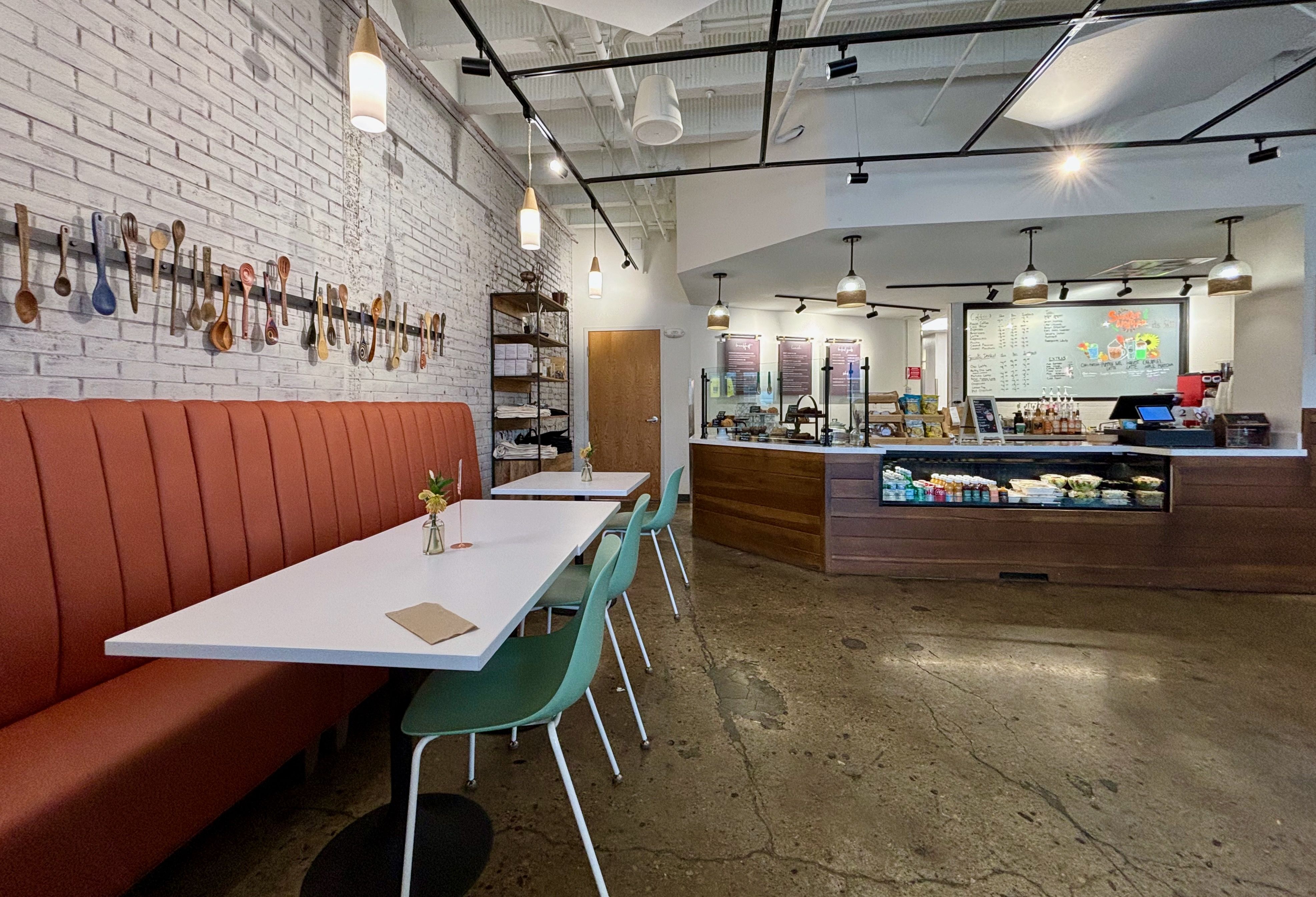 An overview of Freedom a la Cart's cafe, with tables and booths in a seating area and a cafe counter