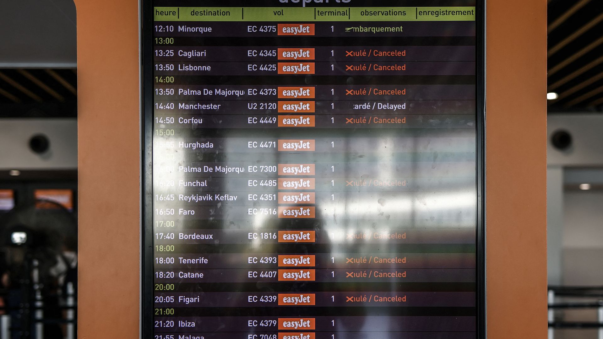 An airport departure board in an orange frame listing flight times and destinations, with an orange "easyJet" logo and a green header reading "départs".