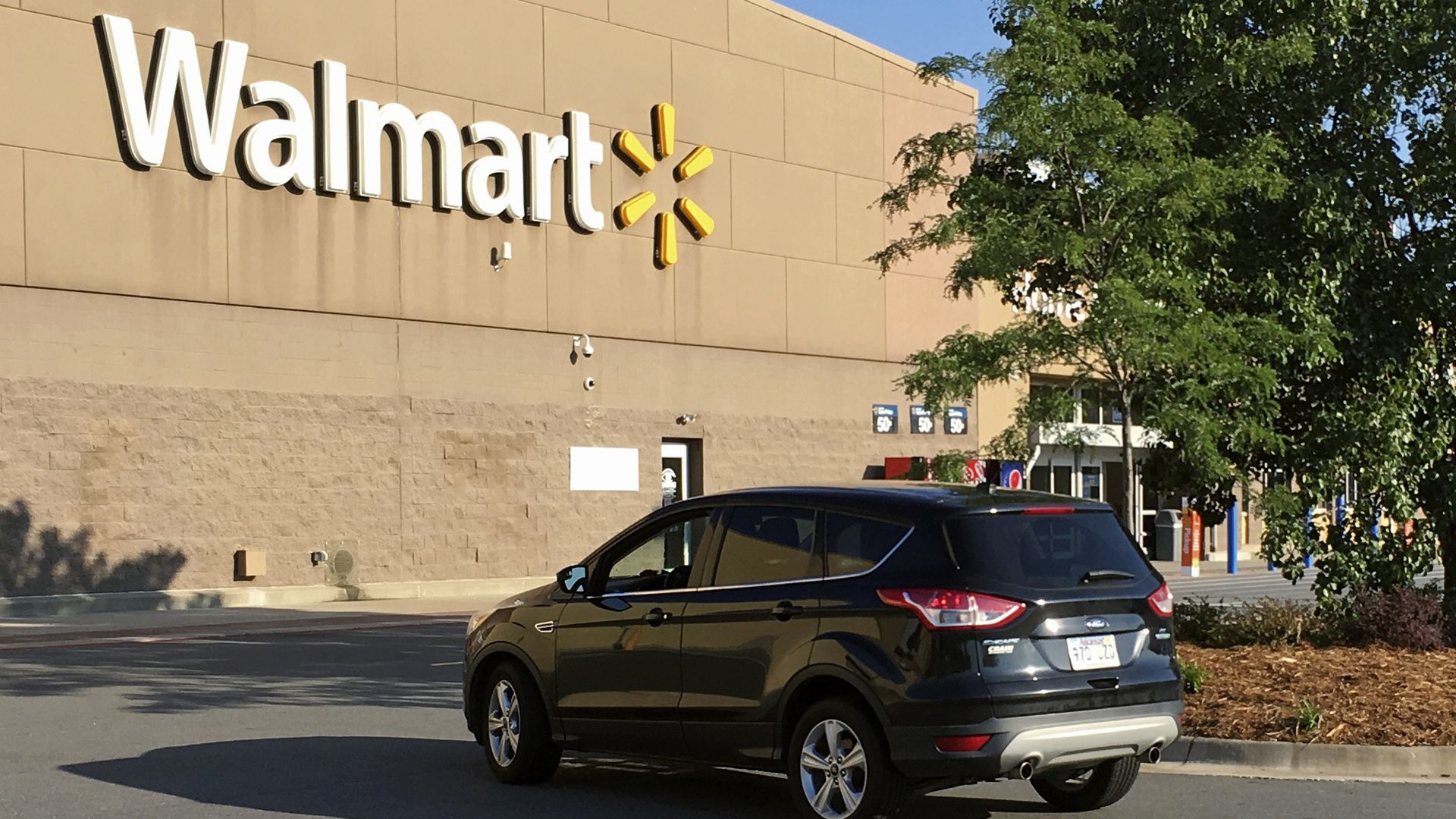 A motorist drives through a Walmart parking lot.