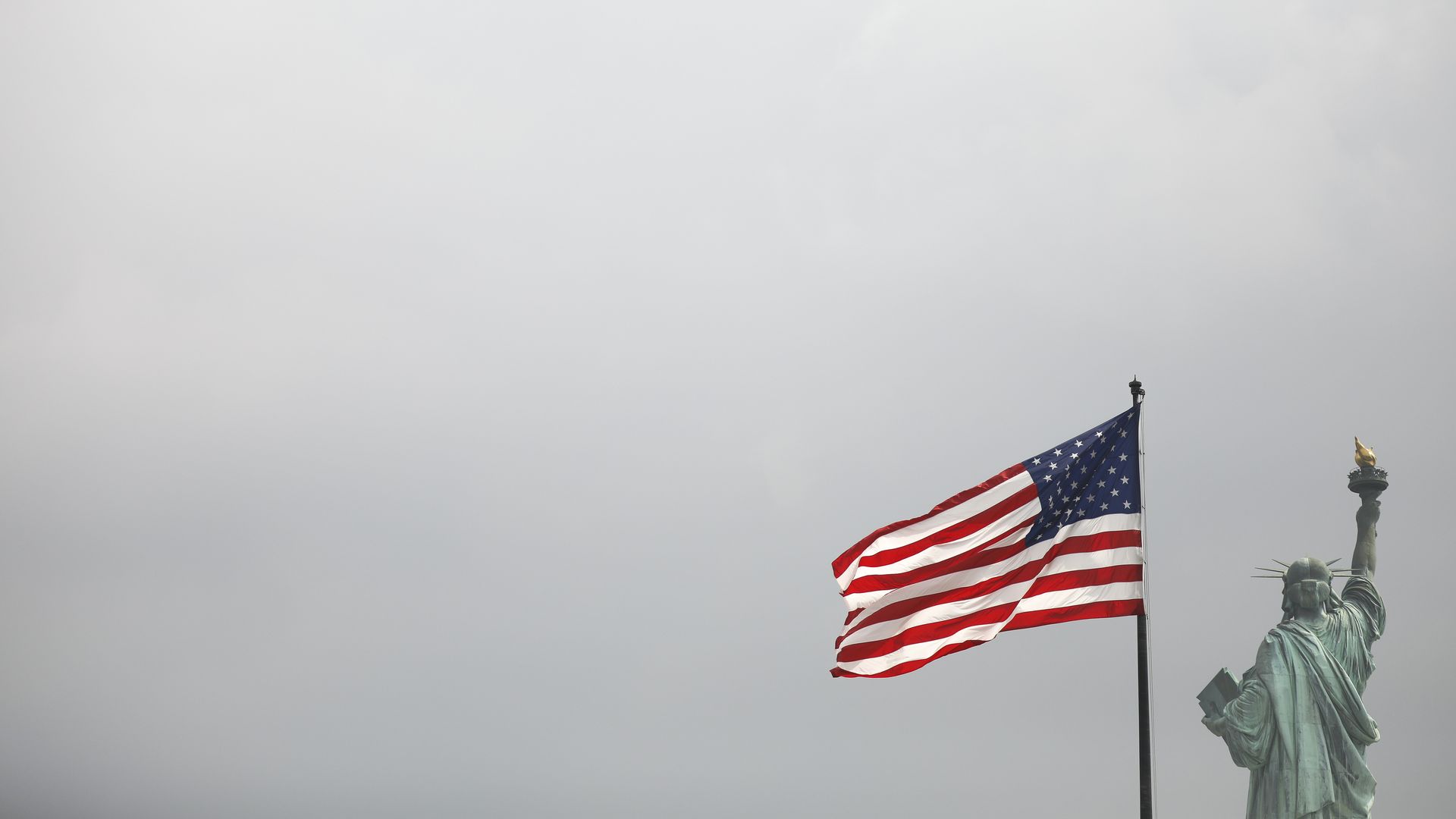 An American flag flying beside the statue of liberty. 
