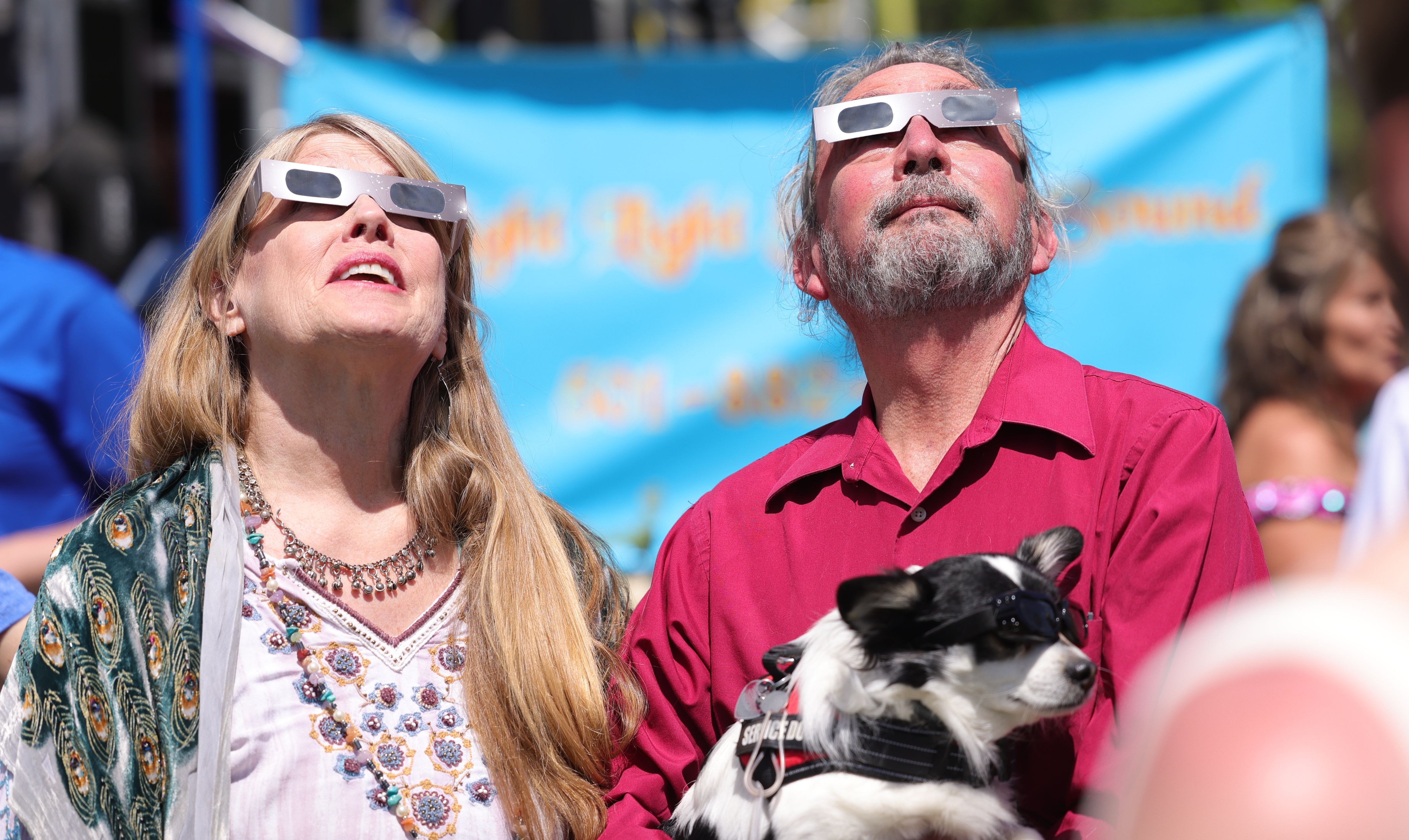 A couple looks at the sun through eclipse glasses. 