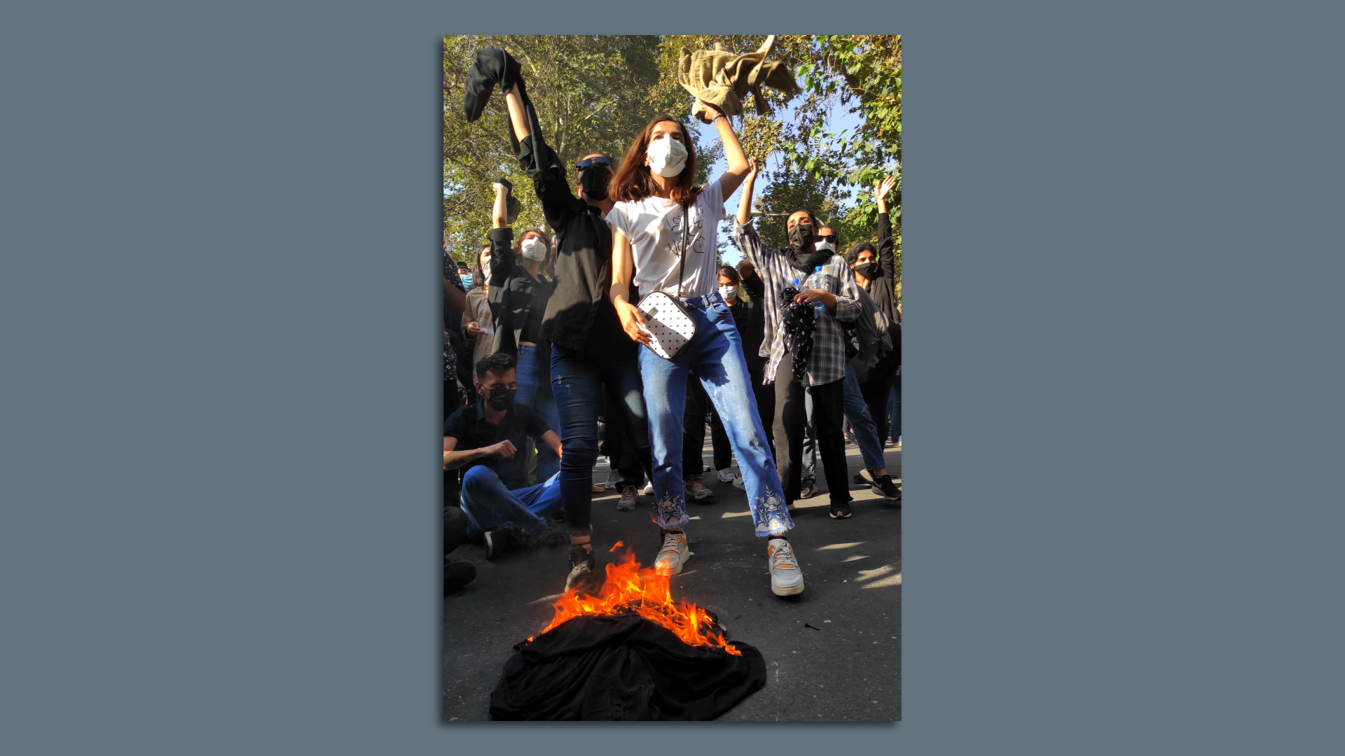 Iranian protesters set their scarves on fire while marching down a street on Oct. 1 in Tehran, Iran. Photo: Getty Images
