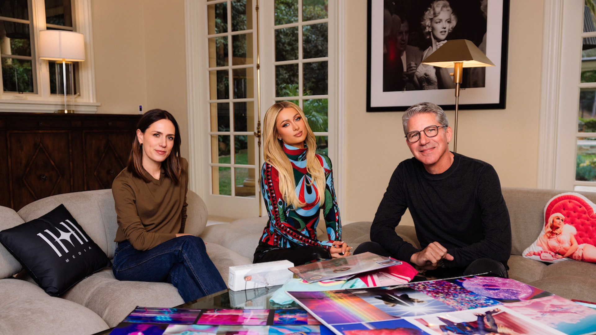 Paris Hilton (center) sits alongside 11:11 Media Chief Commercial & Chief Brand Officer Rachel Webber (left) and 11:11 Media President, Chief Operating Officer, and co-founder Bruce Gersh at Hilton's home in Los Angeles. Photo credit: Kevin Ostajewski.