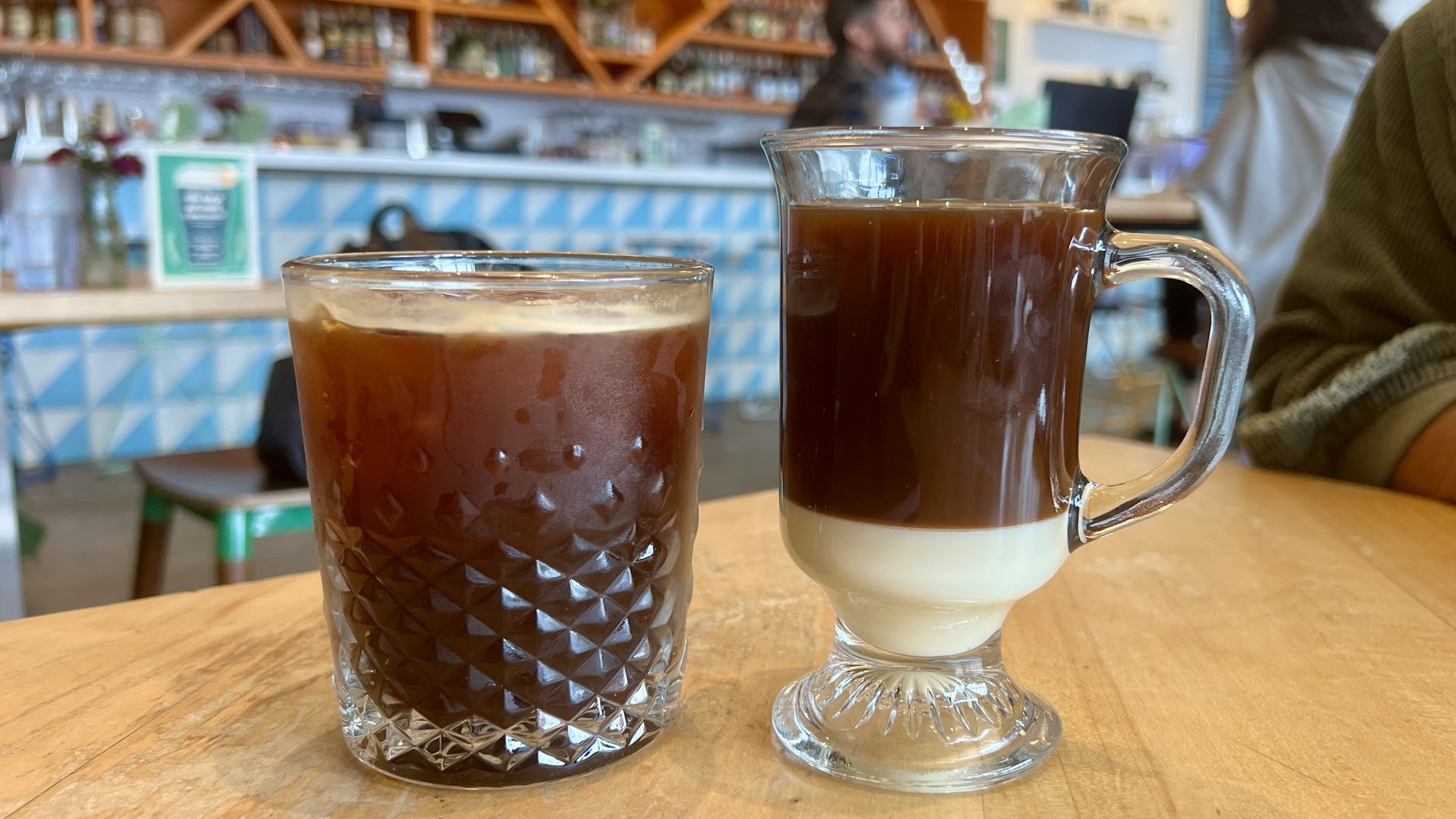 Two clear glasses side by side with coffee drinks in them