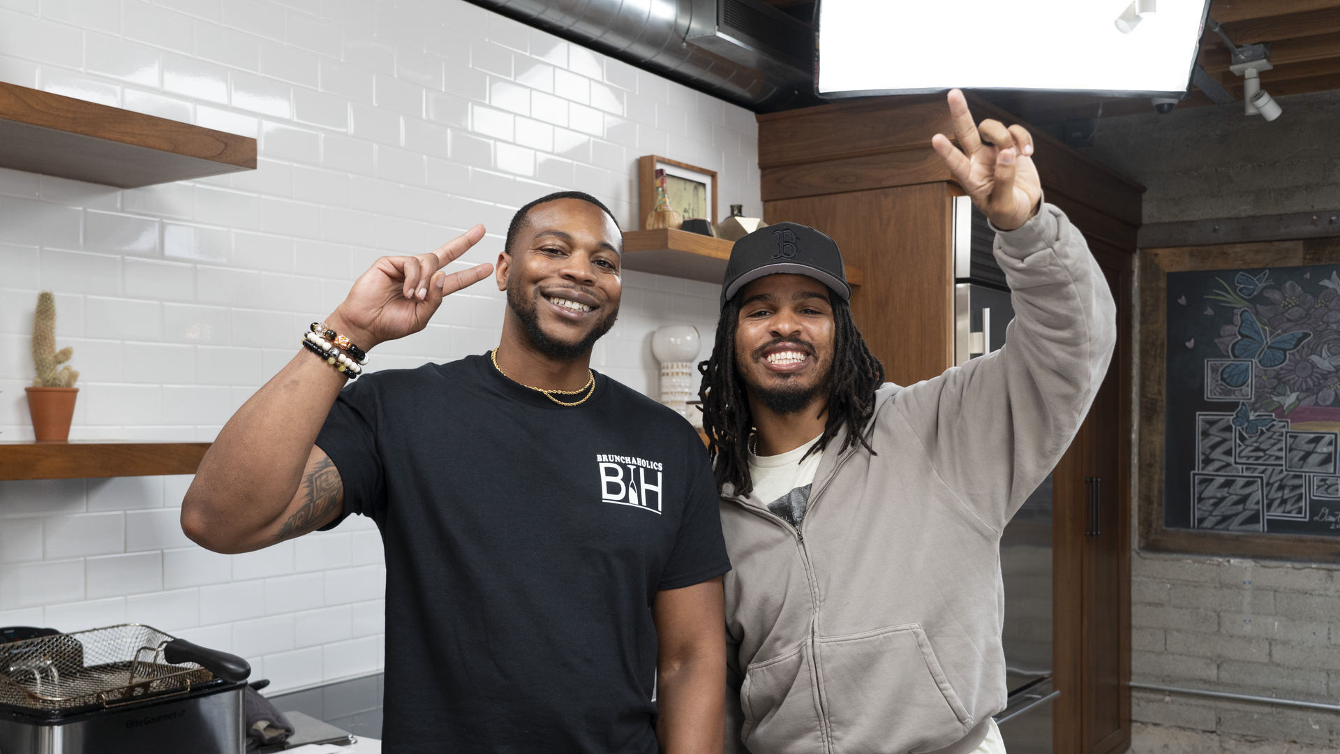 Two men holding up peace hand signs in a restaurant