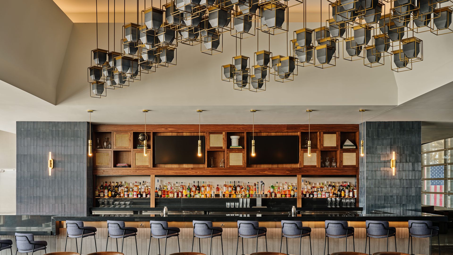 An airport lounge bar with a chandelier sculpture hanging from the ceiling.