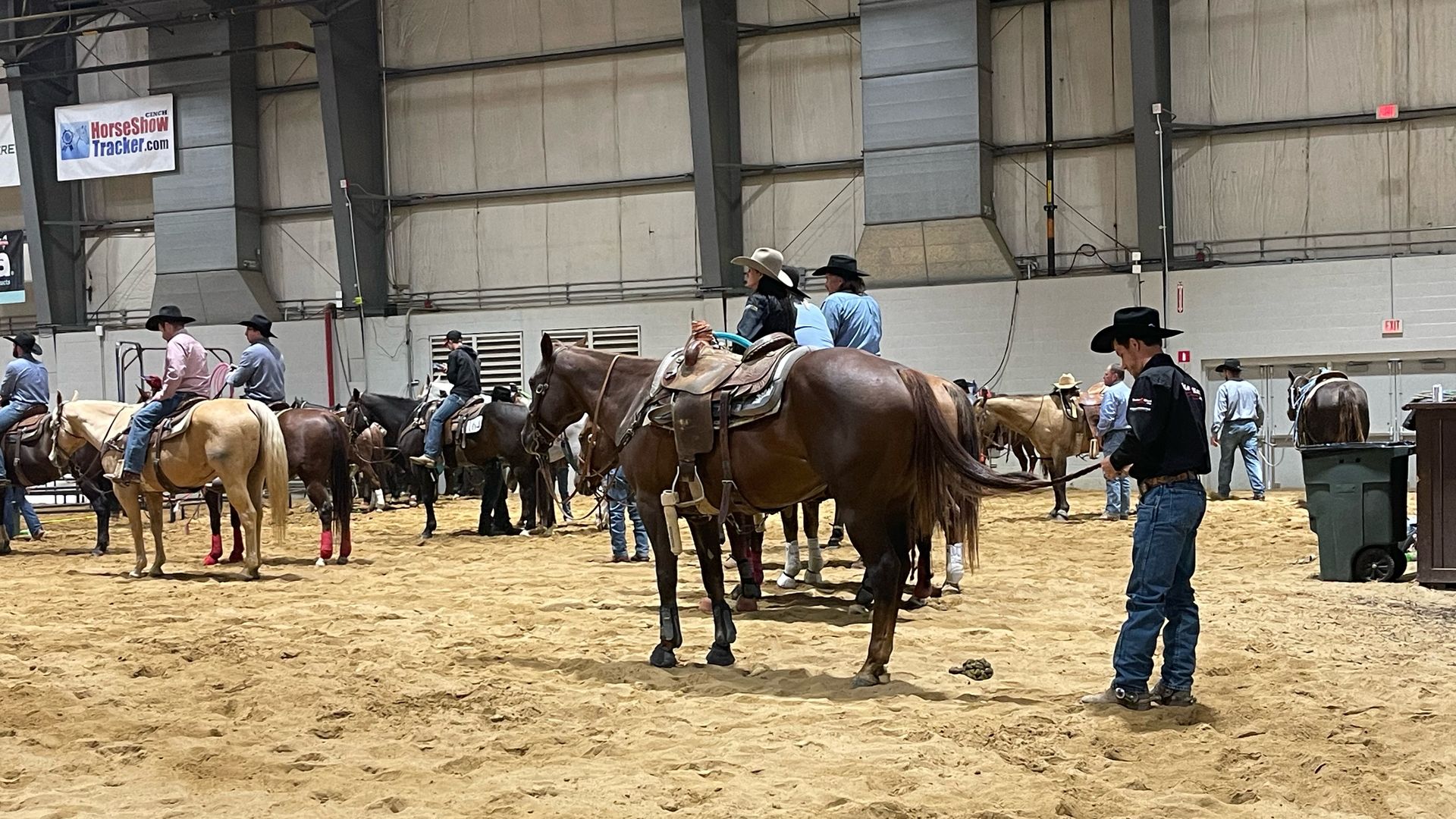 A rider braids his horse's hair while waiting in line to compete. 