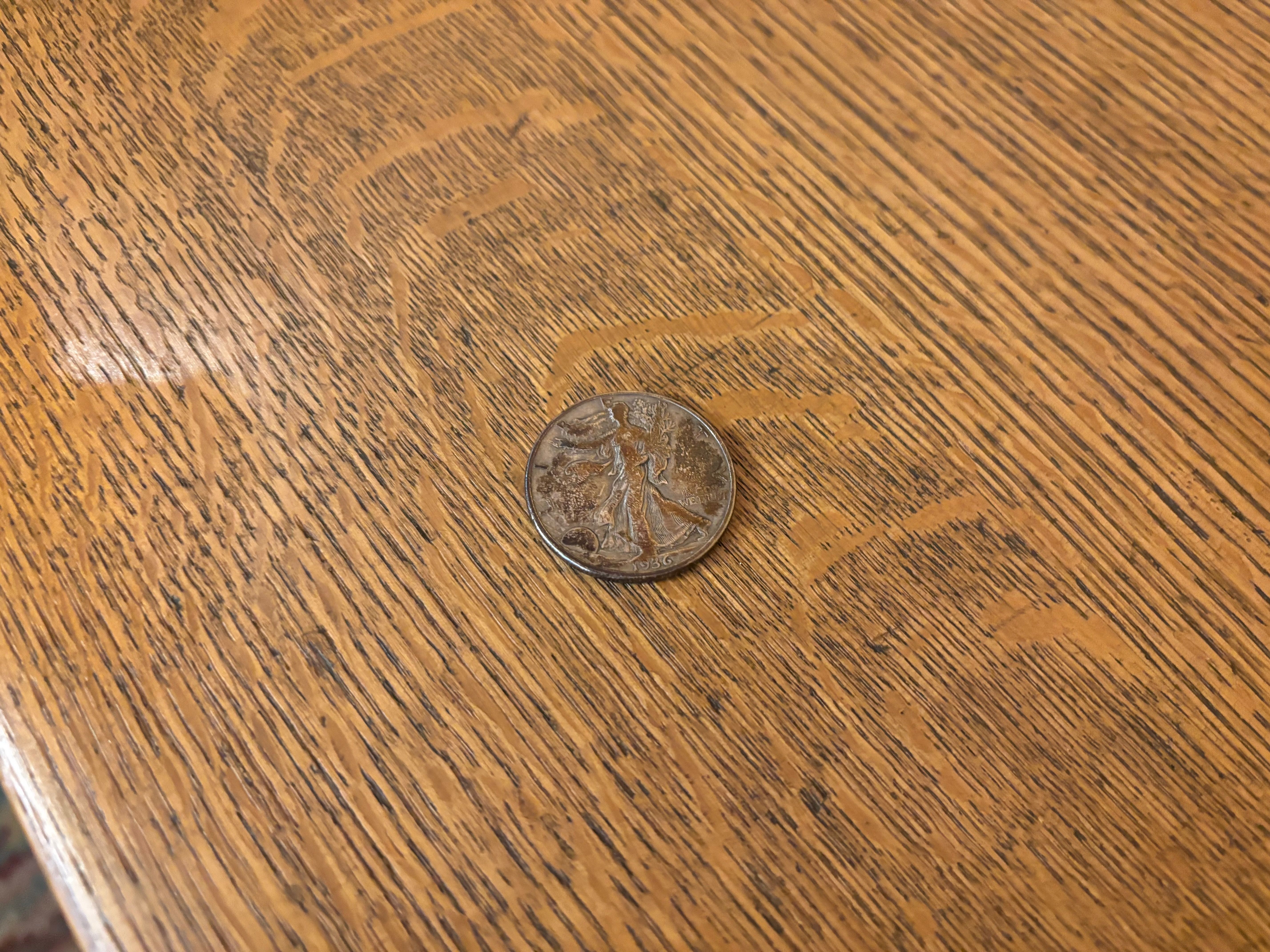 Close-up of a warm, grainy wooden table with two overlapping coins near the bottom edge, their silver surfaces catching light.