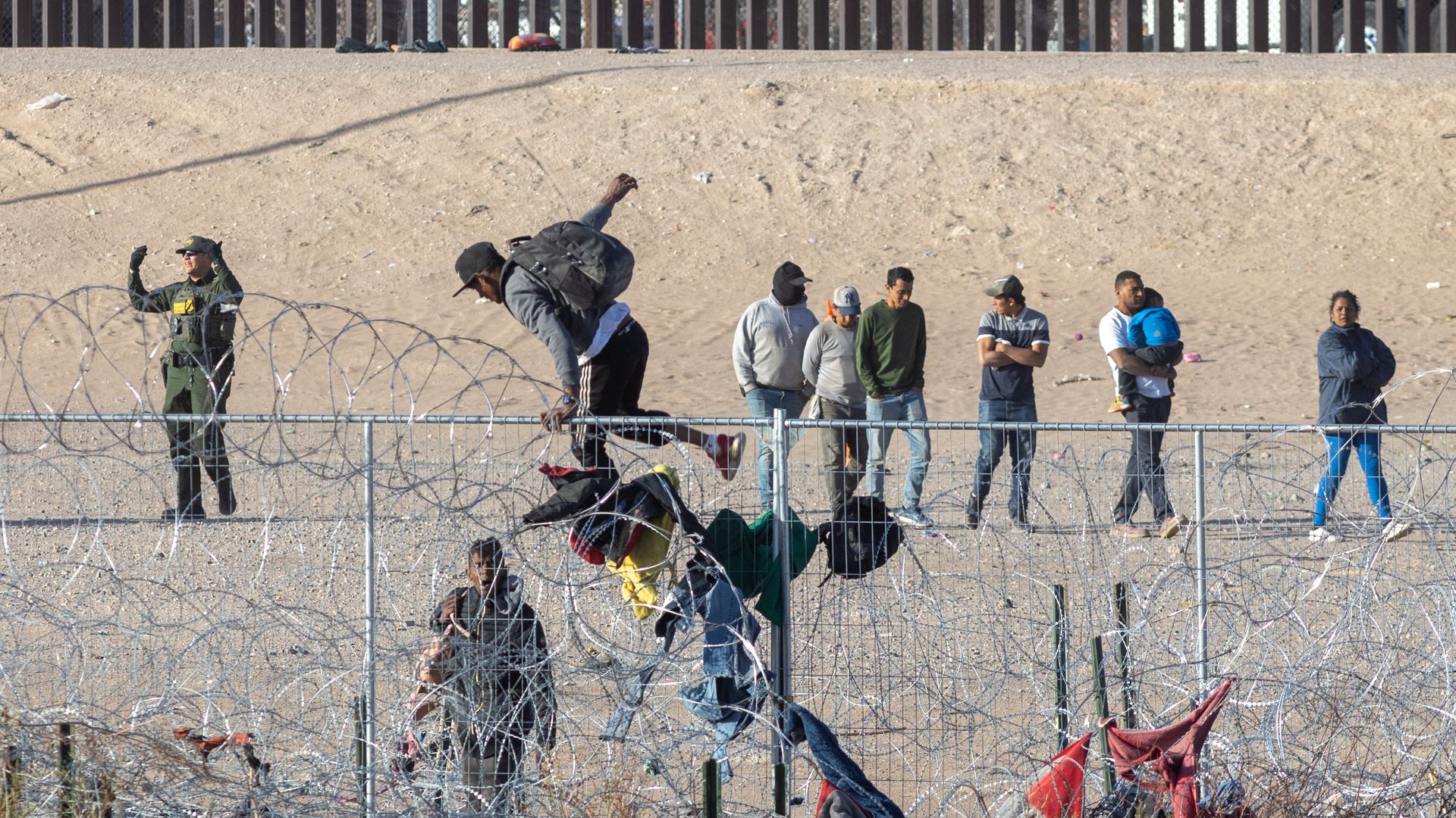 People scaling a fence along the Texas-Mexico border.