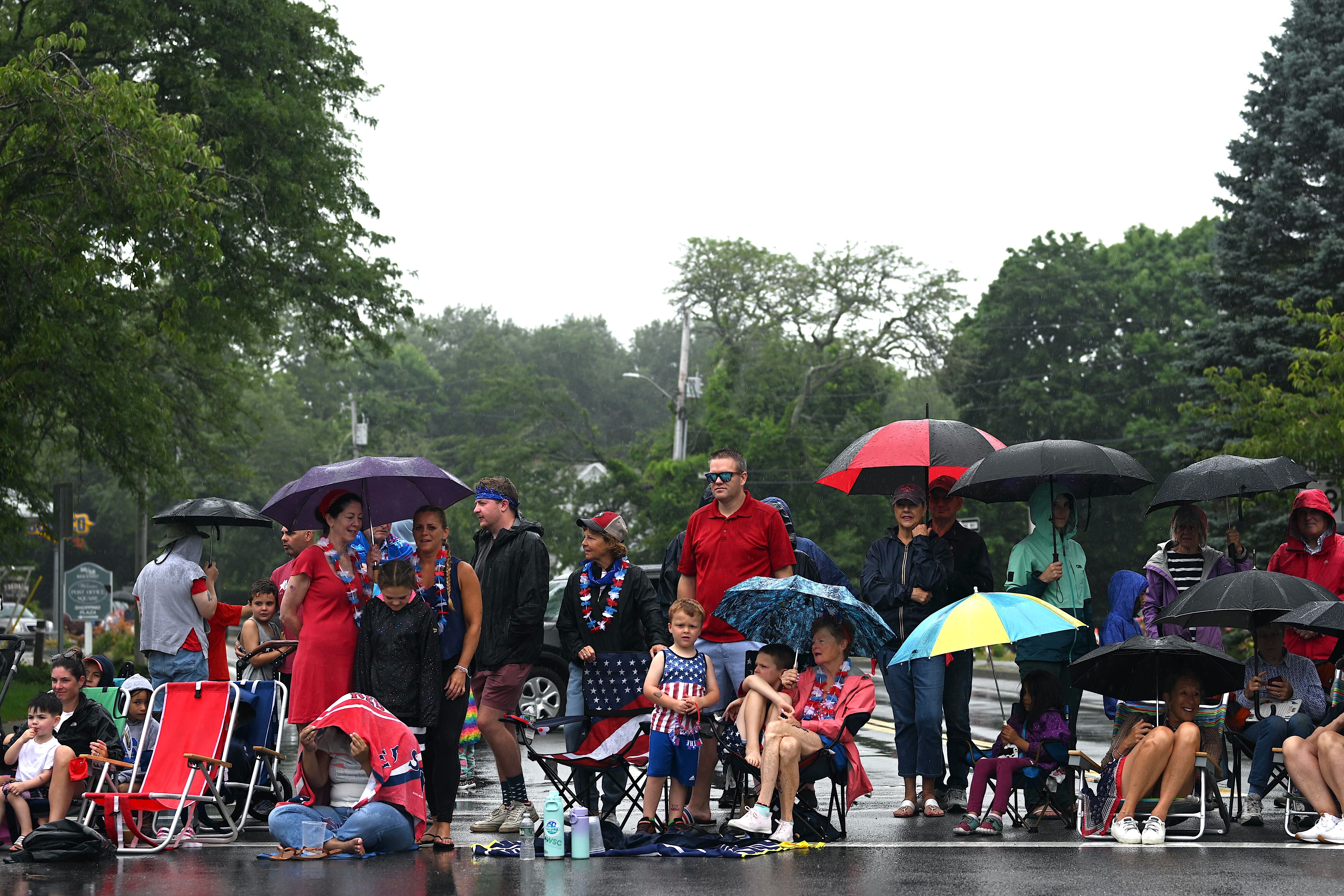 People huddle under umbrellas during a rainstorm before a Fourth of July parade in Cape Cod on July 4, 2023 in Orleans, Massachusetts. Today marks the 247th anniversary of the United States' Declaration of Independence from England. 