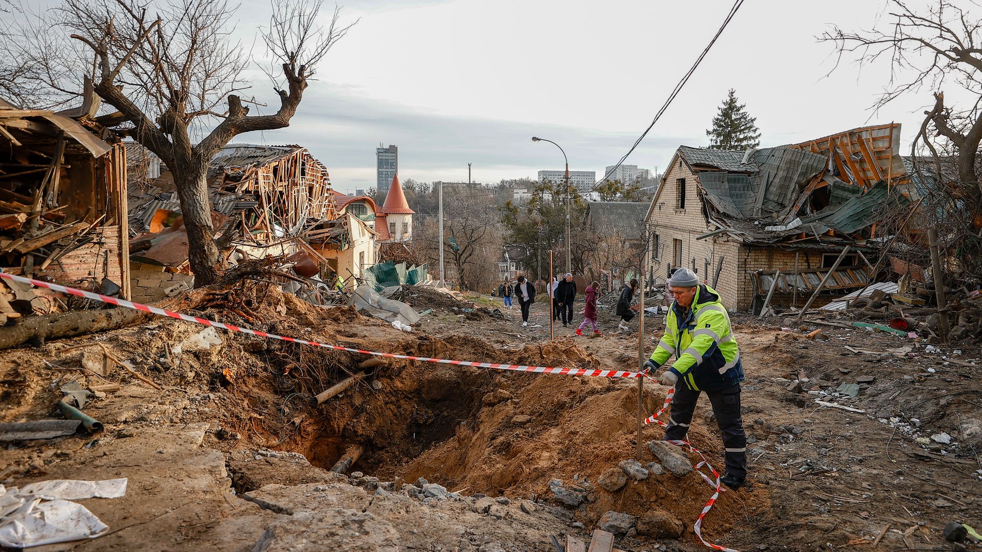 A person setting up safety tape around a crater from a Russian missile attack in the Solomyansk district of Kyiv on Jan. 1.