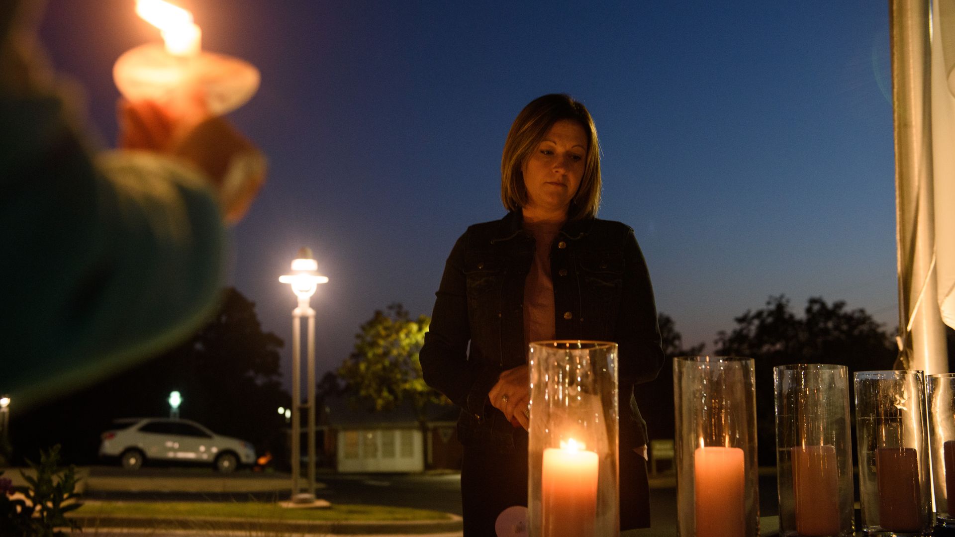  A woman lights candles in honor of the 5 victims who died in the Hedingham neighborhood shooting