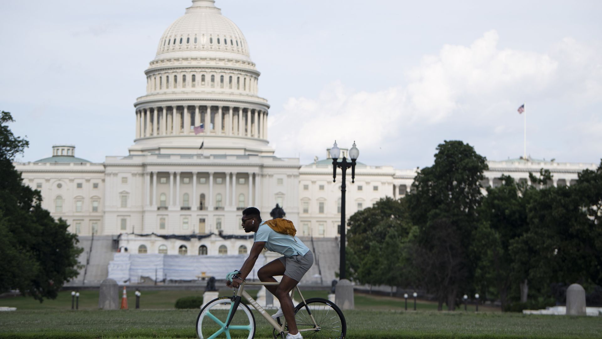 Photo of a man riding a bicycle in front of the U.S. Capitol building.