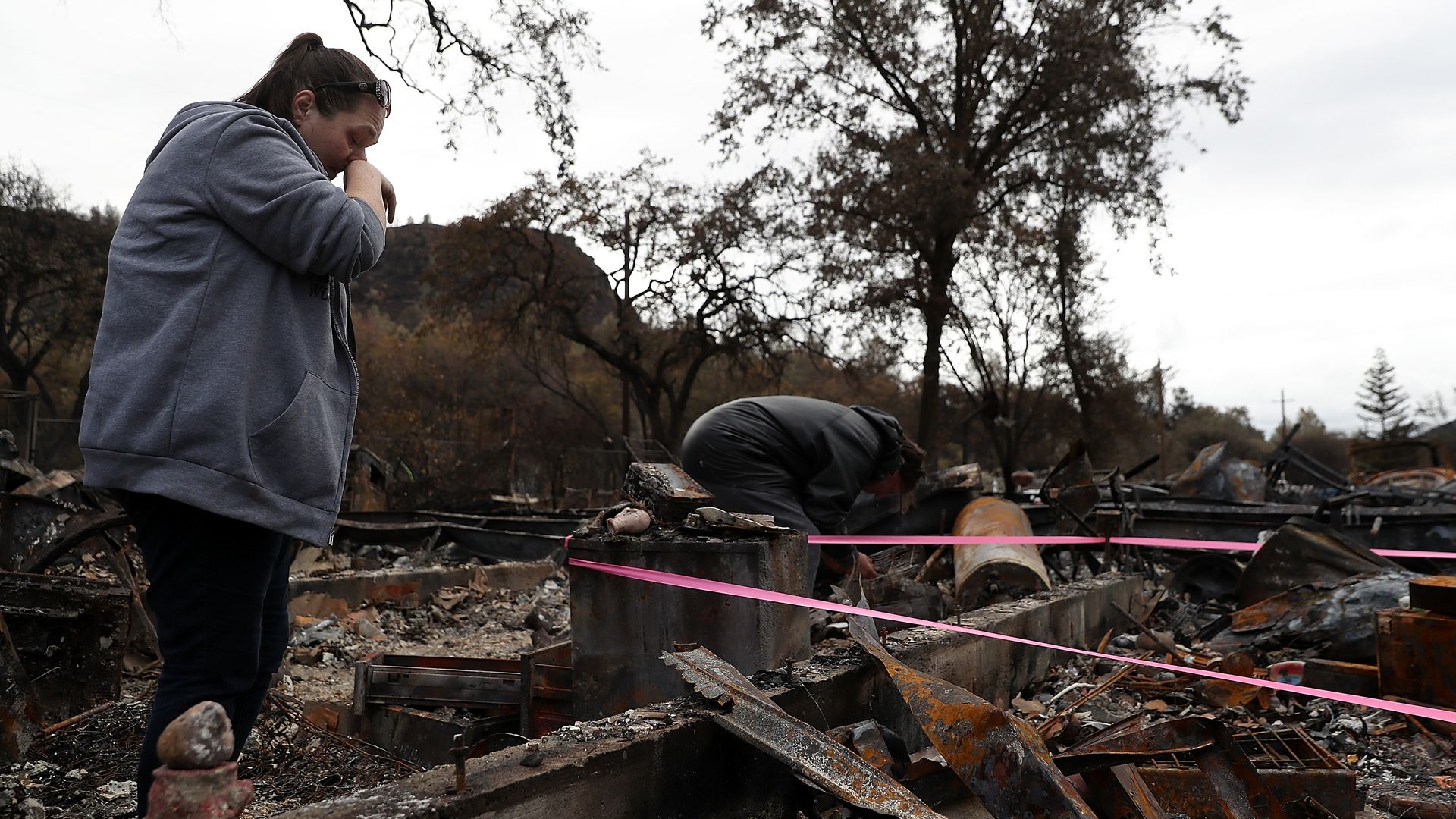 A woman stands in burned ruins of her home.
