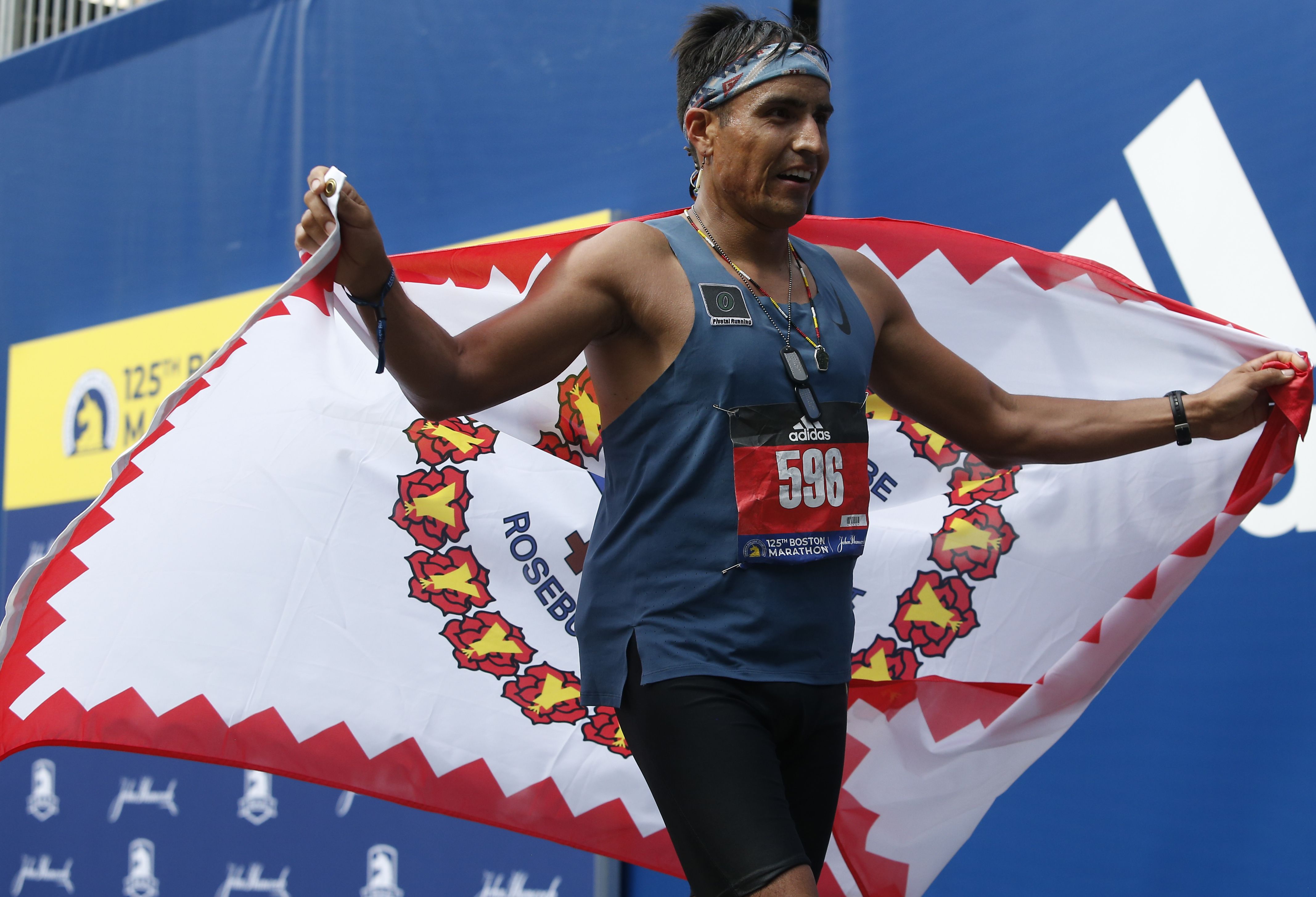 Marathon runner holding an Indigenous flag behind him