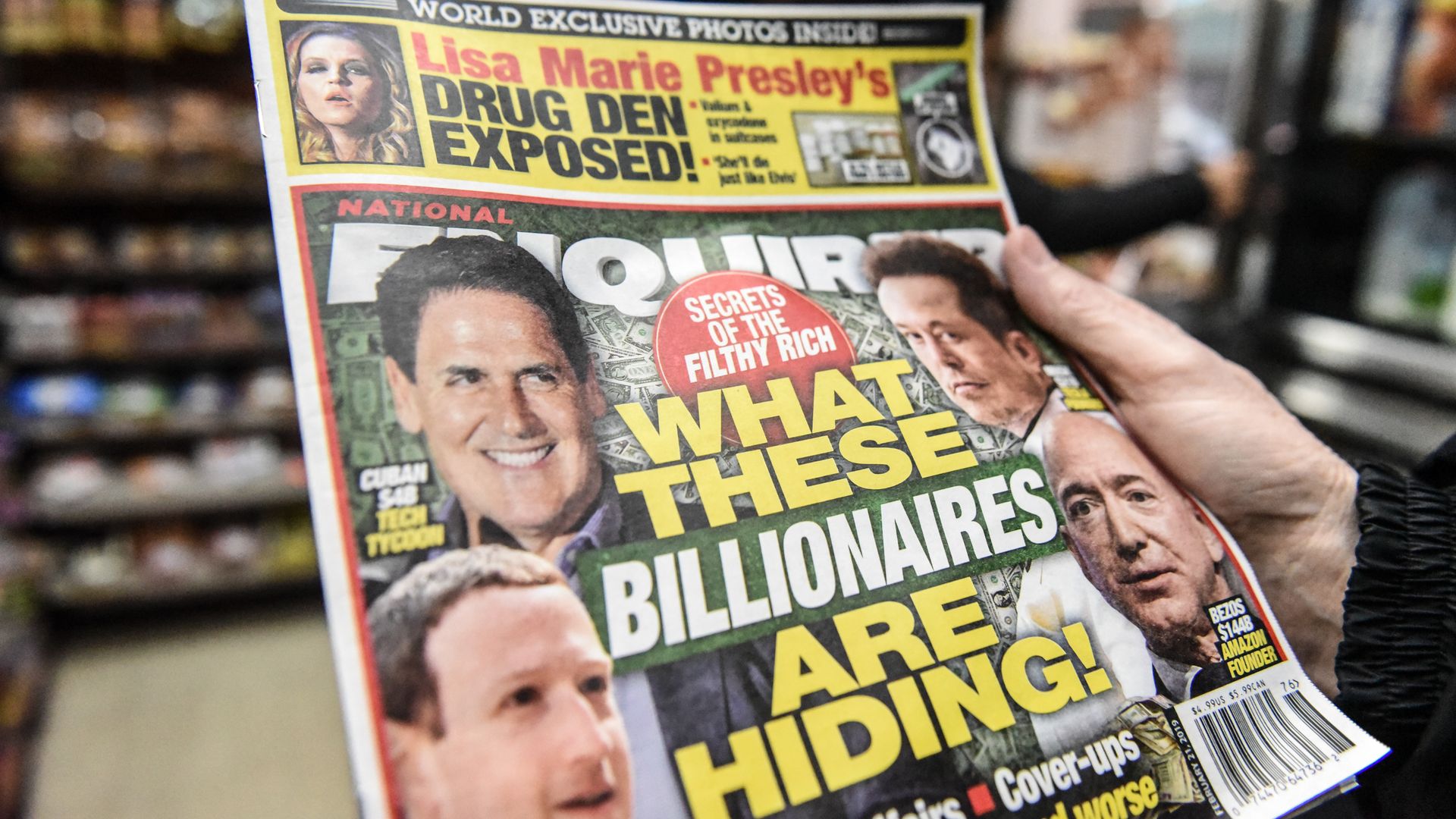 In this image, a copy of the National Enquirer is held up close to the camera by an unseen person. 