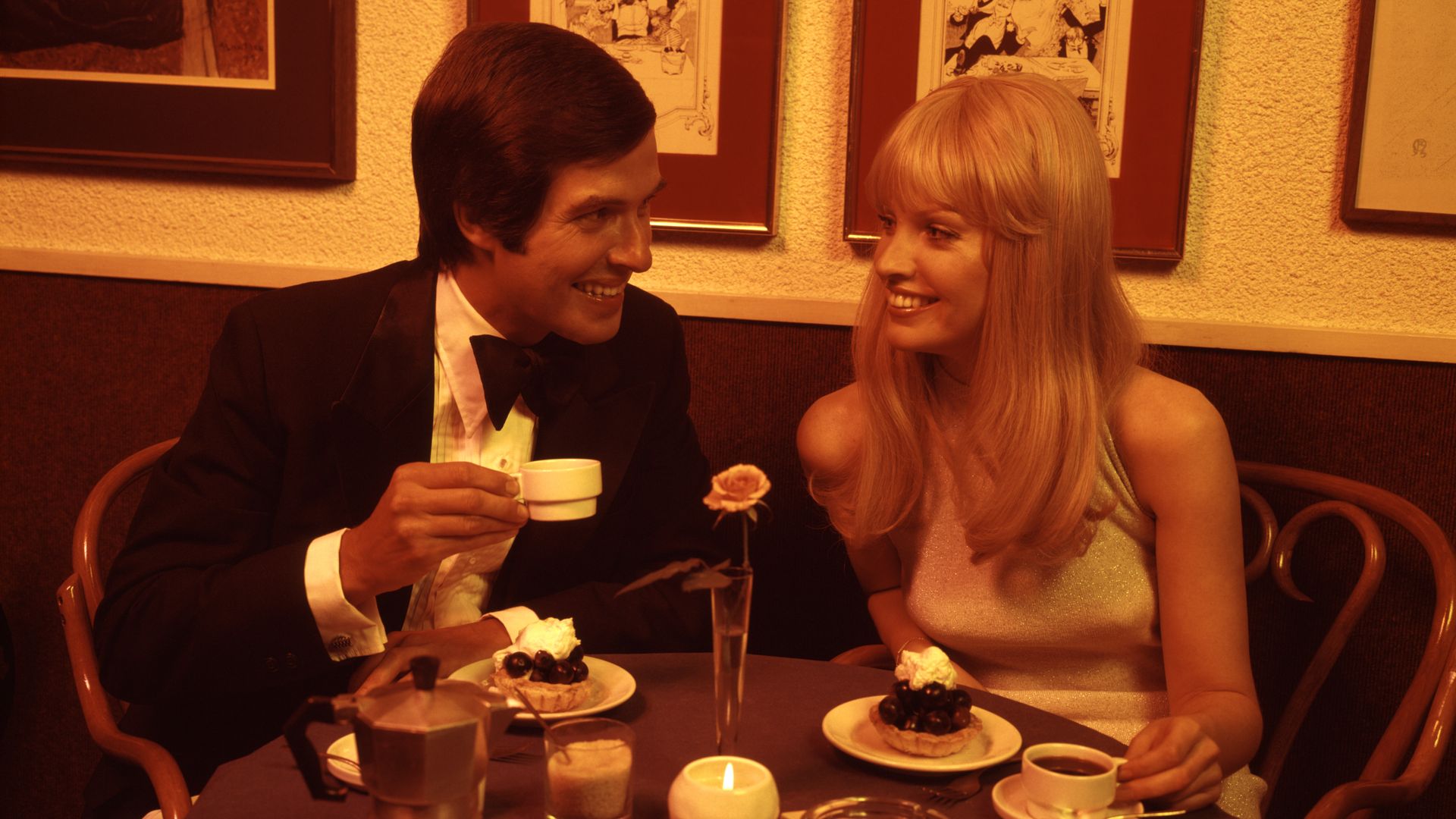 A couple eats dessert at a restaurant in a vintage photo