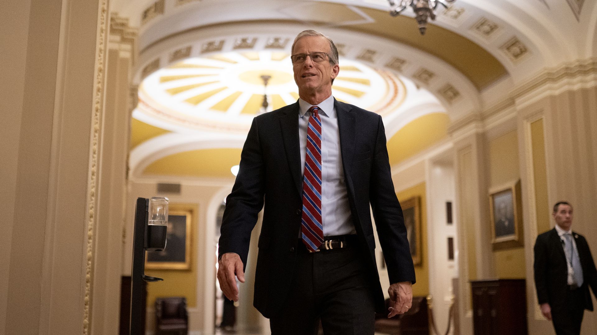 A person in a suit and tie walks in a hallway