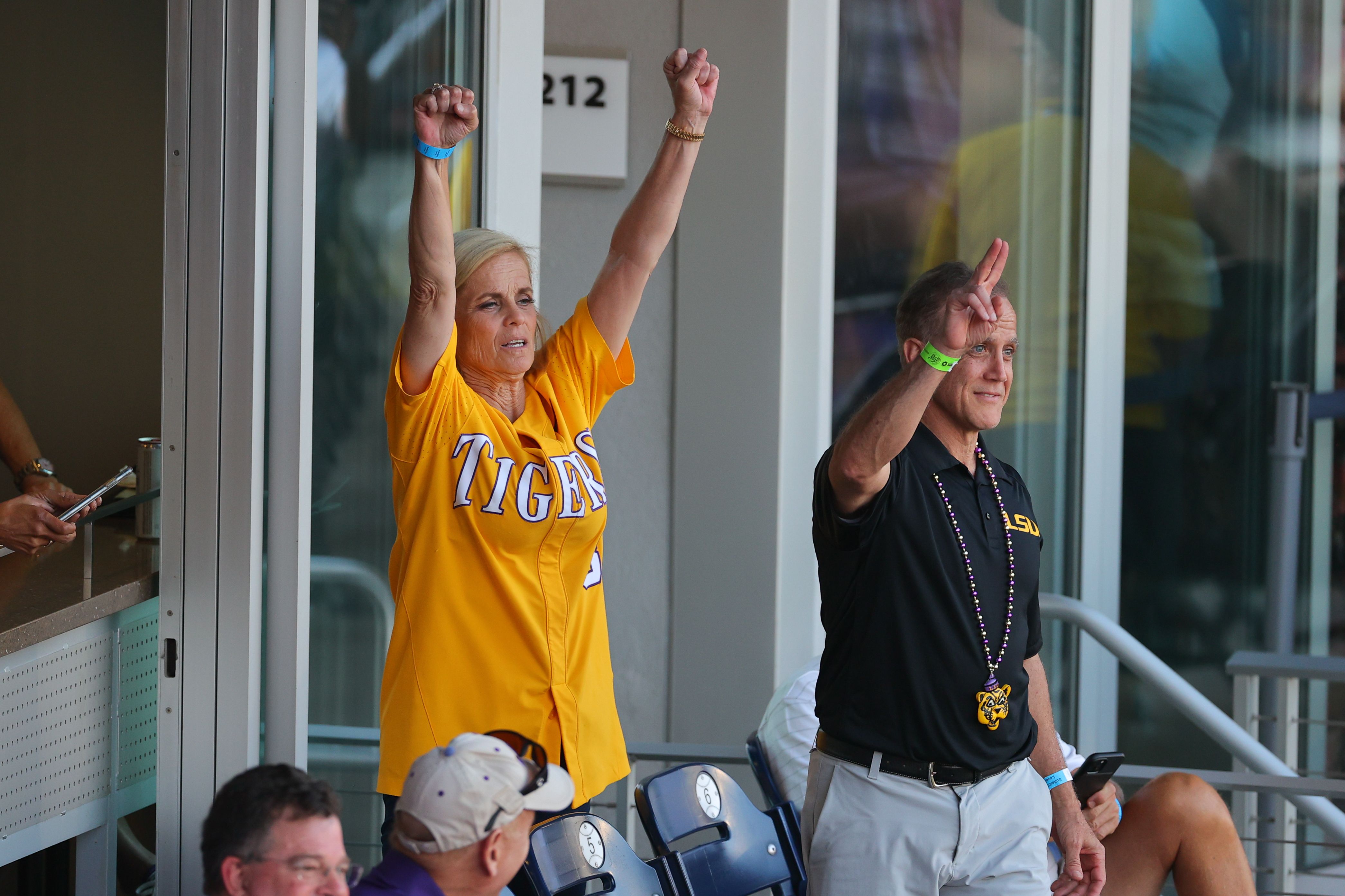 LSU women's basketball coach Kim Mulkey raises her arms to celebrate the LSU men's baseball team