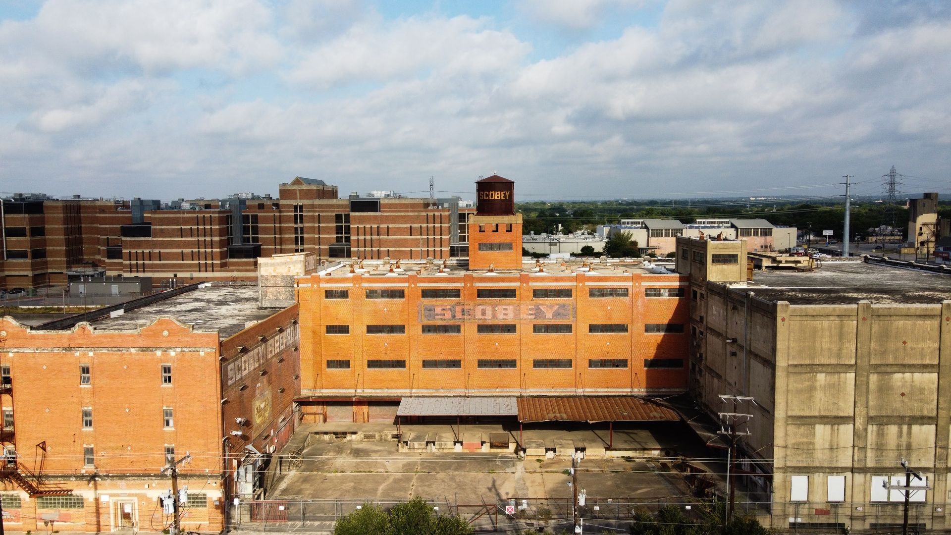 The empty, brick Scobey complex sits with a view of the city behind it.