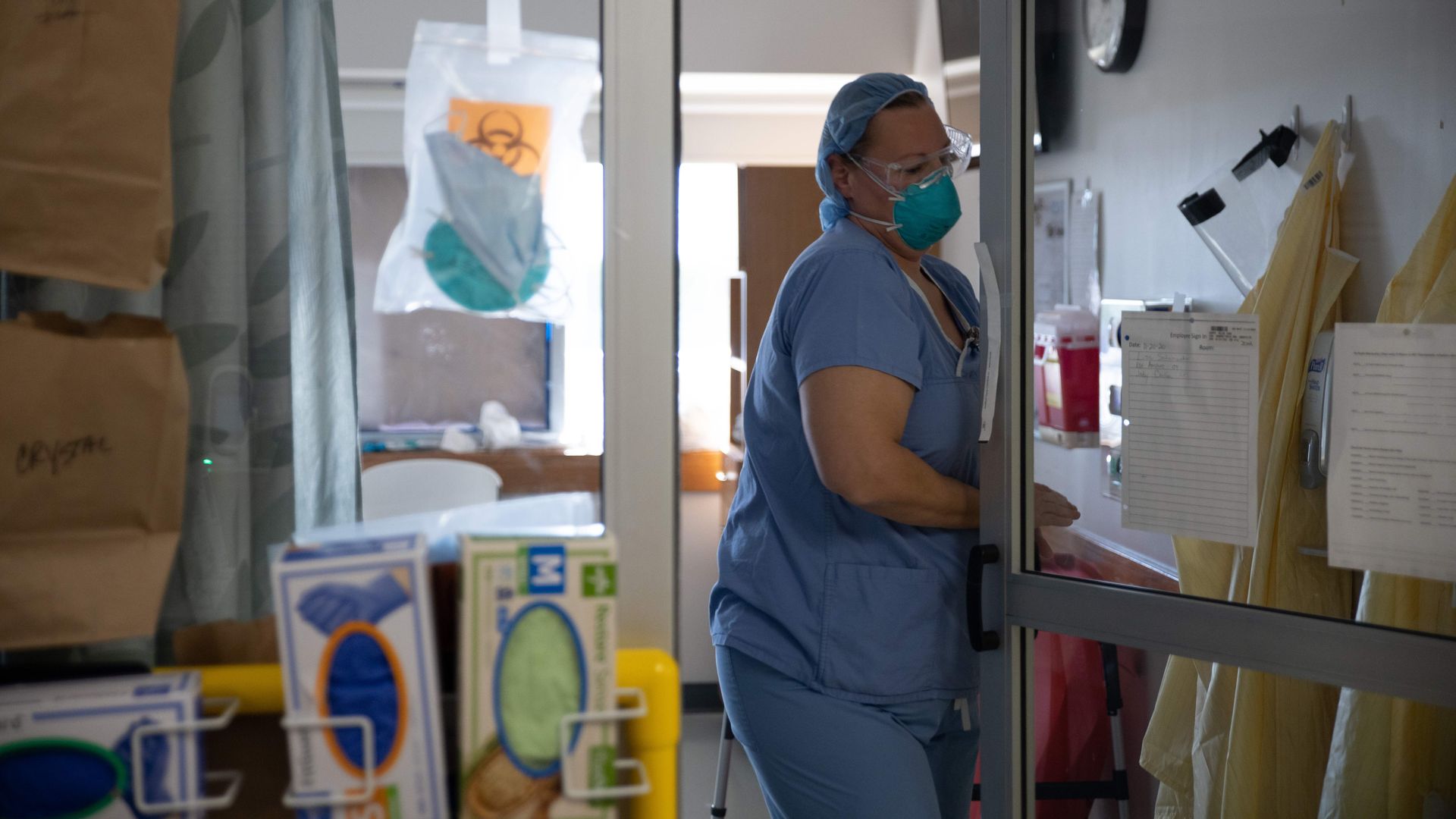 A medical professional wearing PPE opens a door