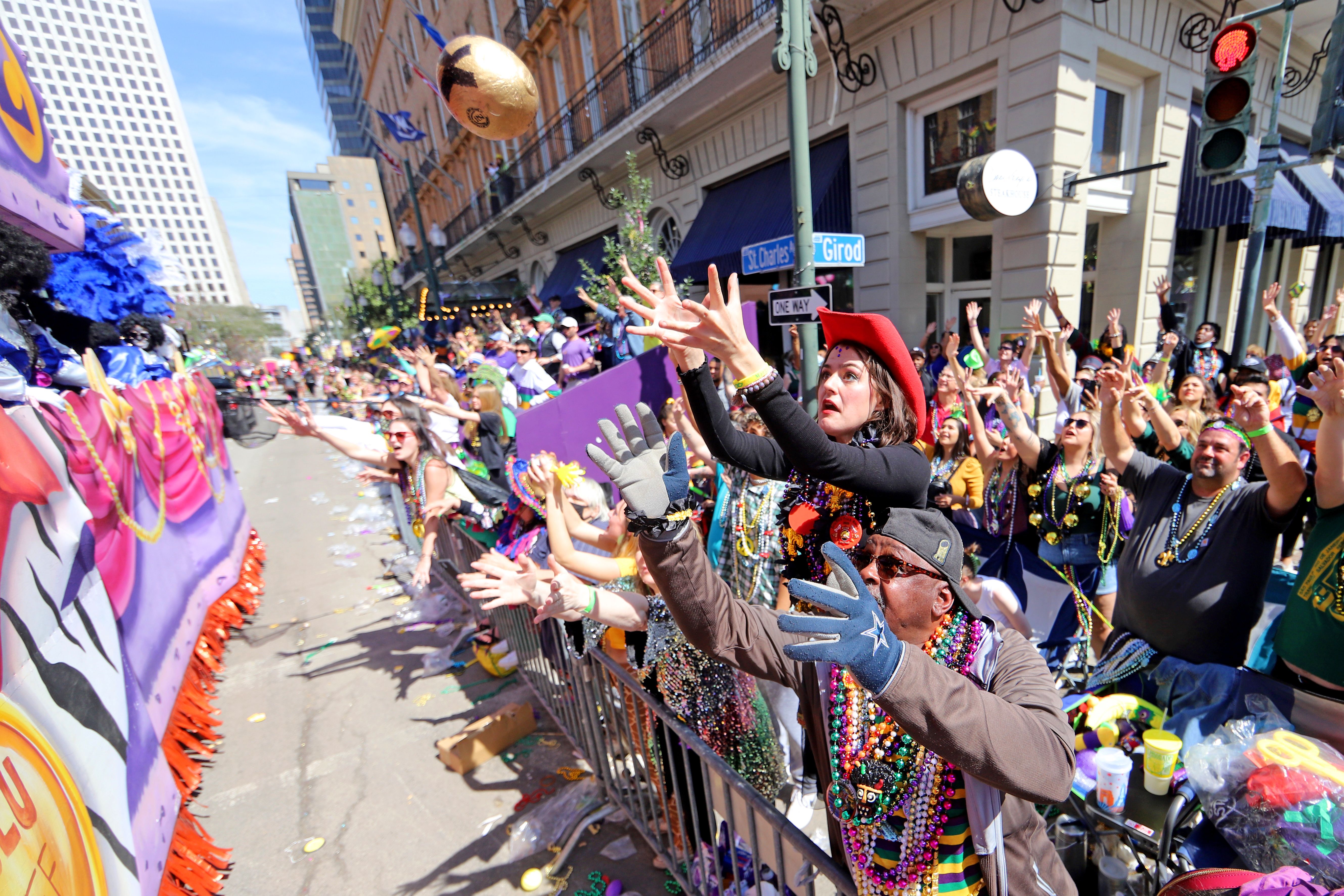 parade-goers at Mardi Gras reach for items tossed from floats 