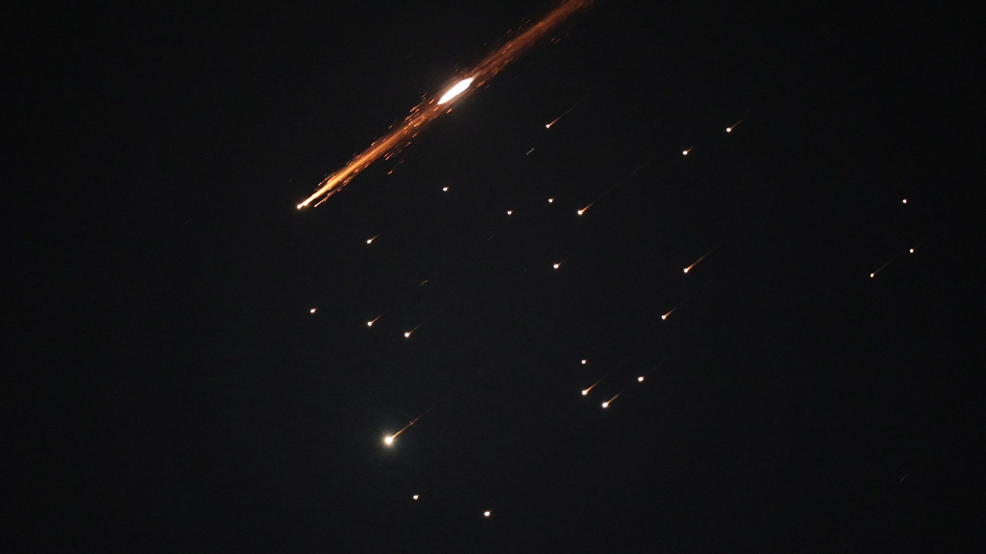 A night sky, streaked with red-orange missile salvos.