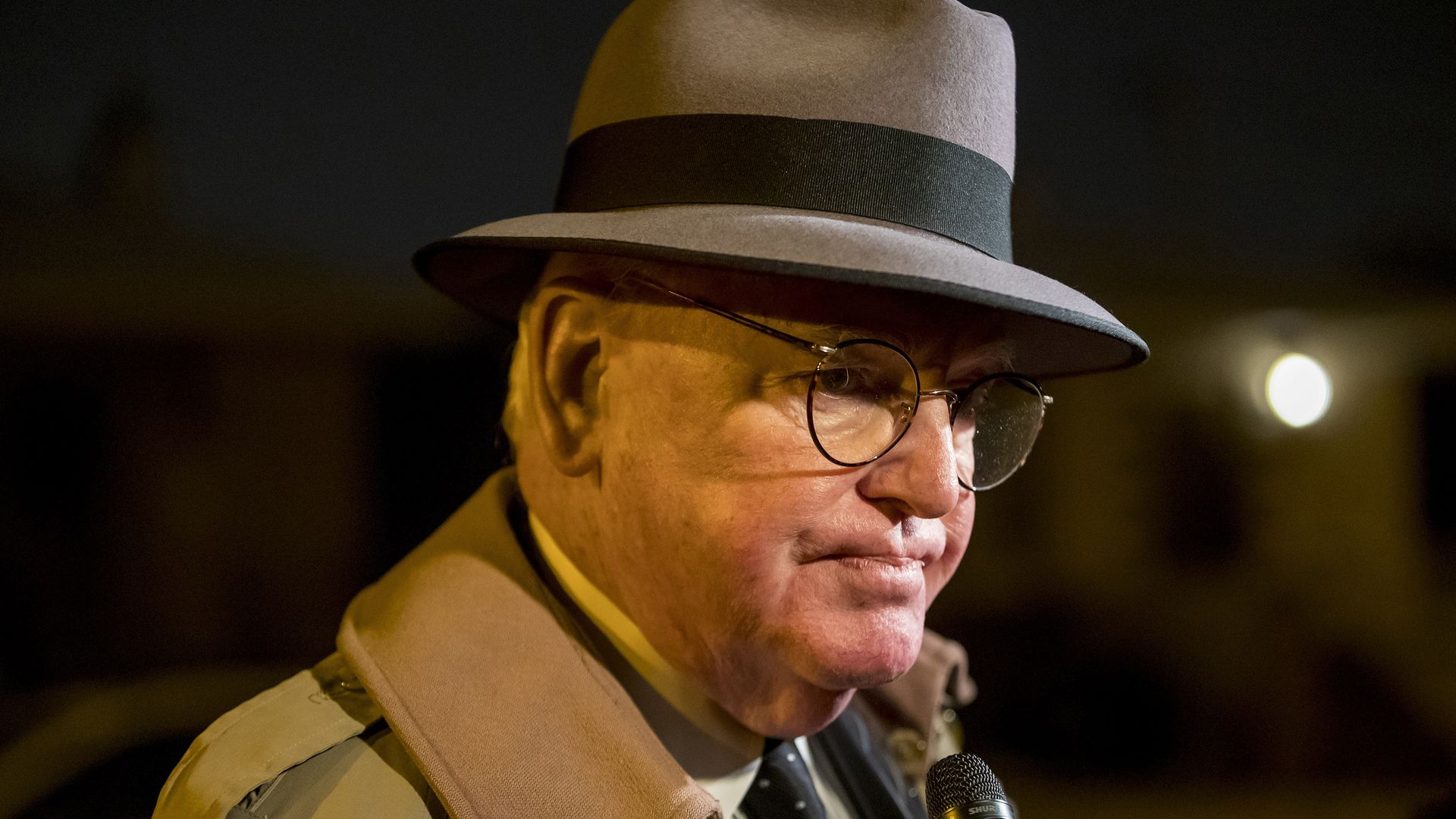 Photo of a man answering questions from a reporter.