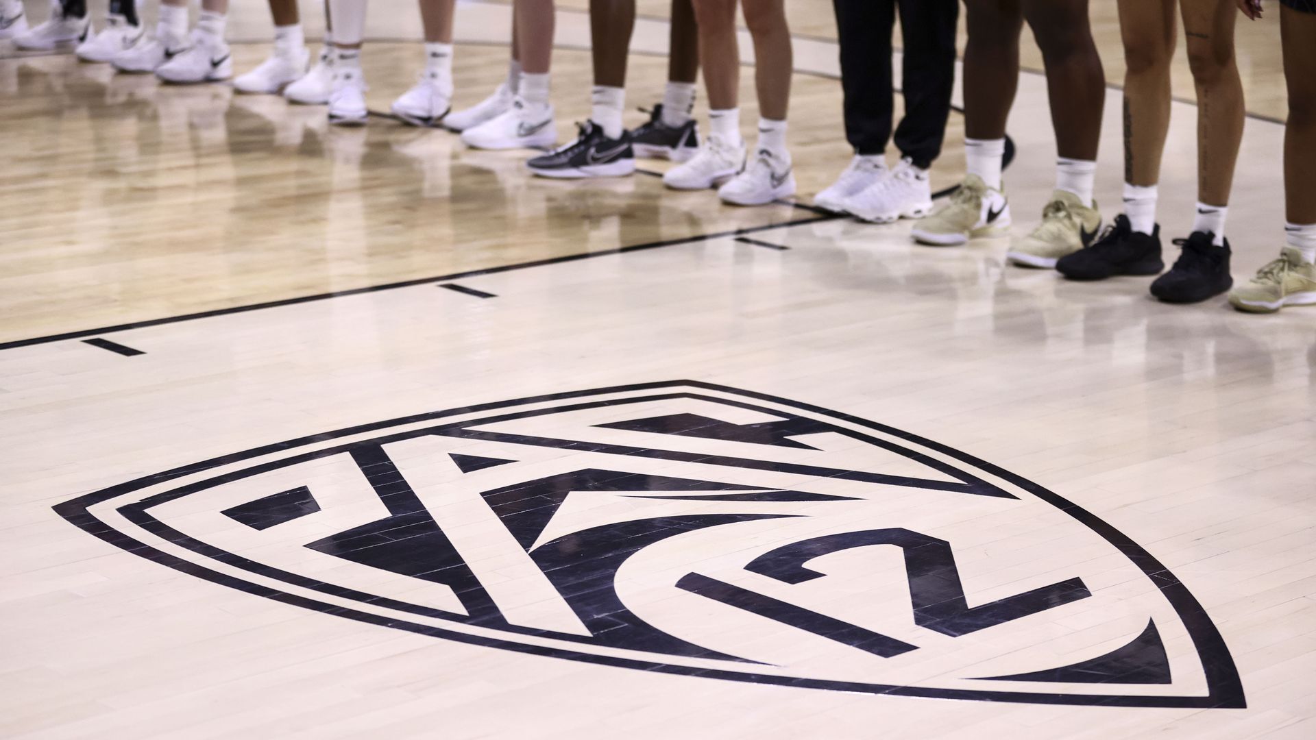 A photo of a logo reading "Pac 12" on the floor on an athletic gym.
