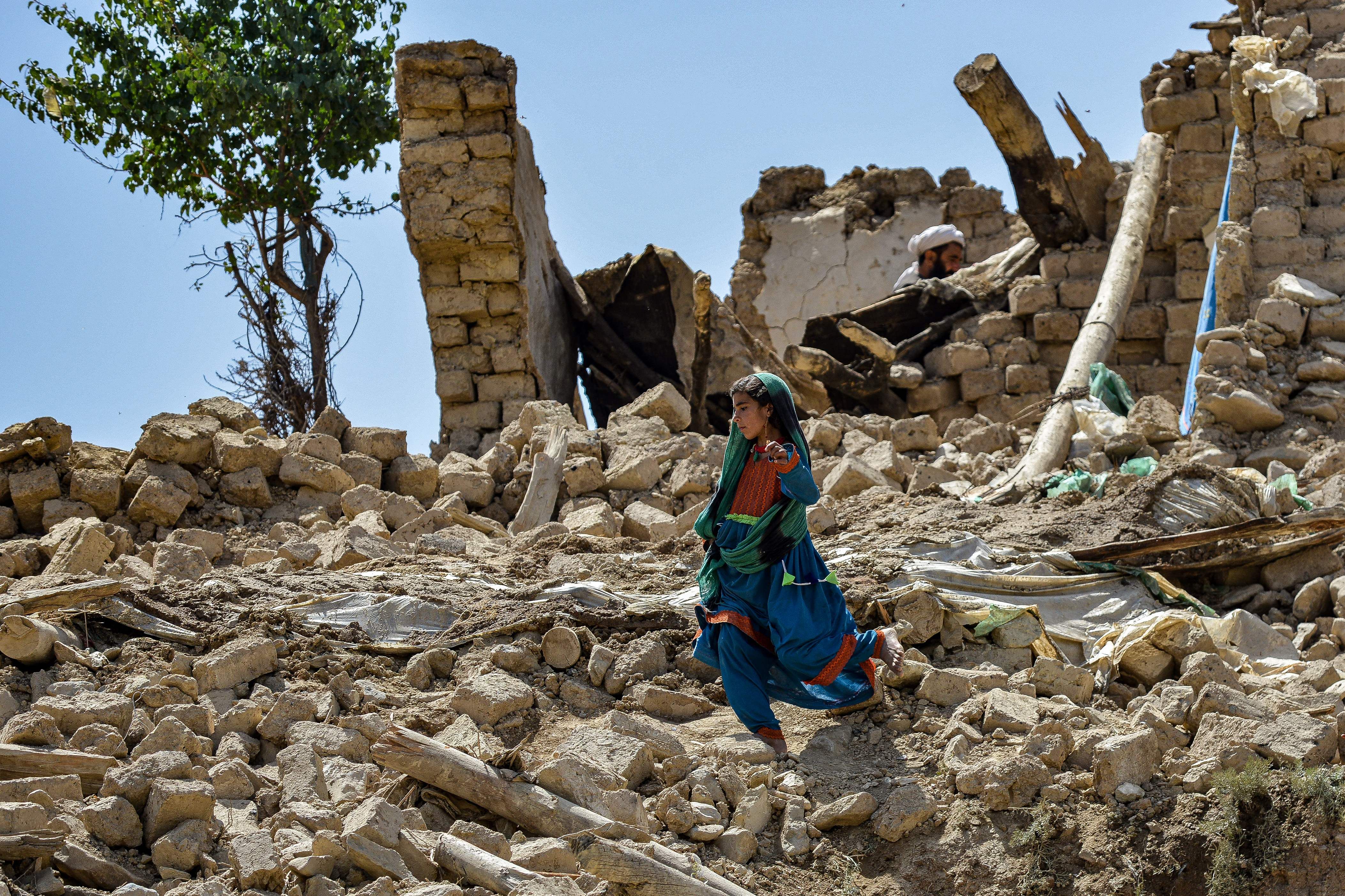 A young girl walks over rubble. 