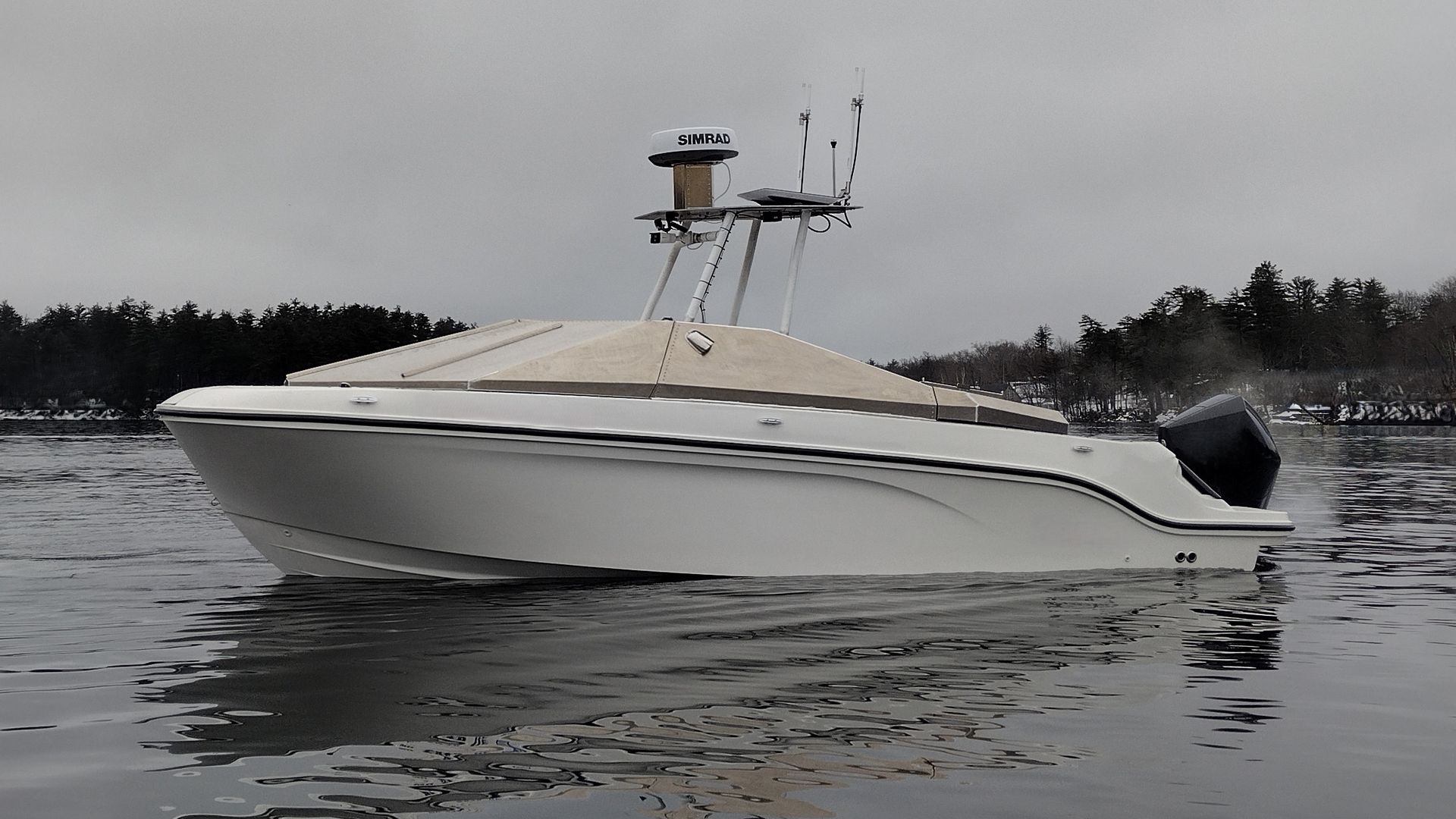 An unmanned surface vessel, white in color, sits on the water. The sky above is grey.