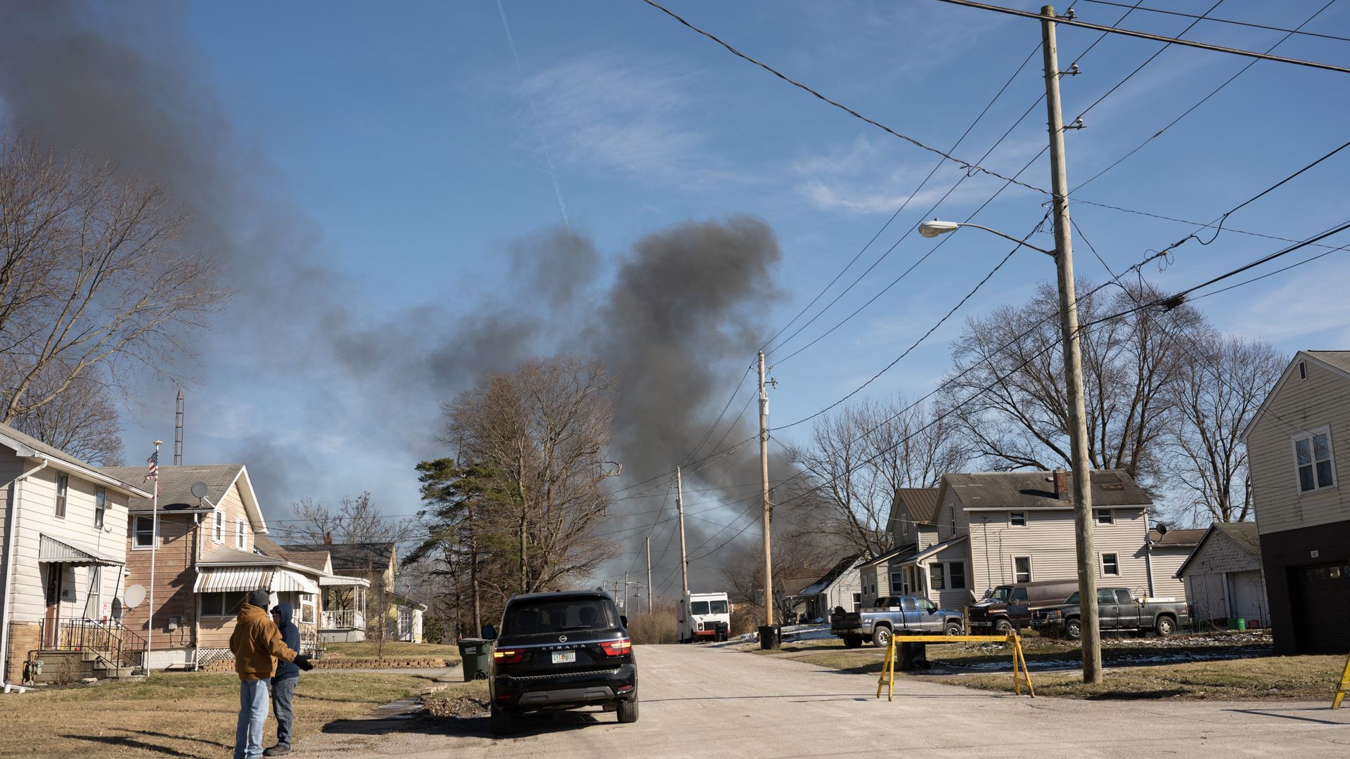 Smoke billowing in the distance with a neighborhood in the foreground