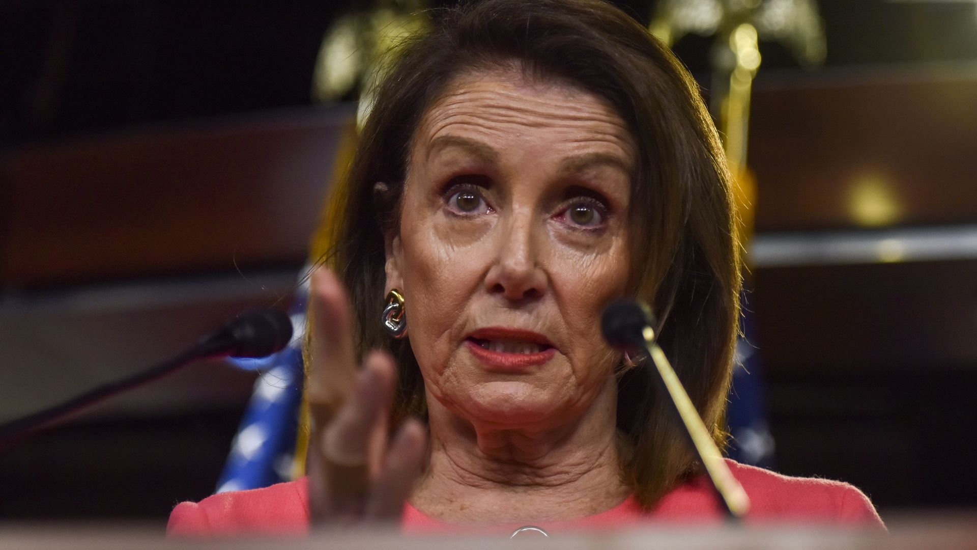 In this image, Pelosi gestures from behind a podium.