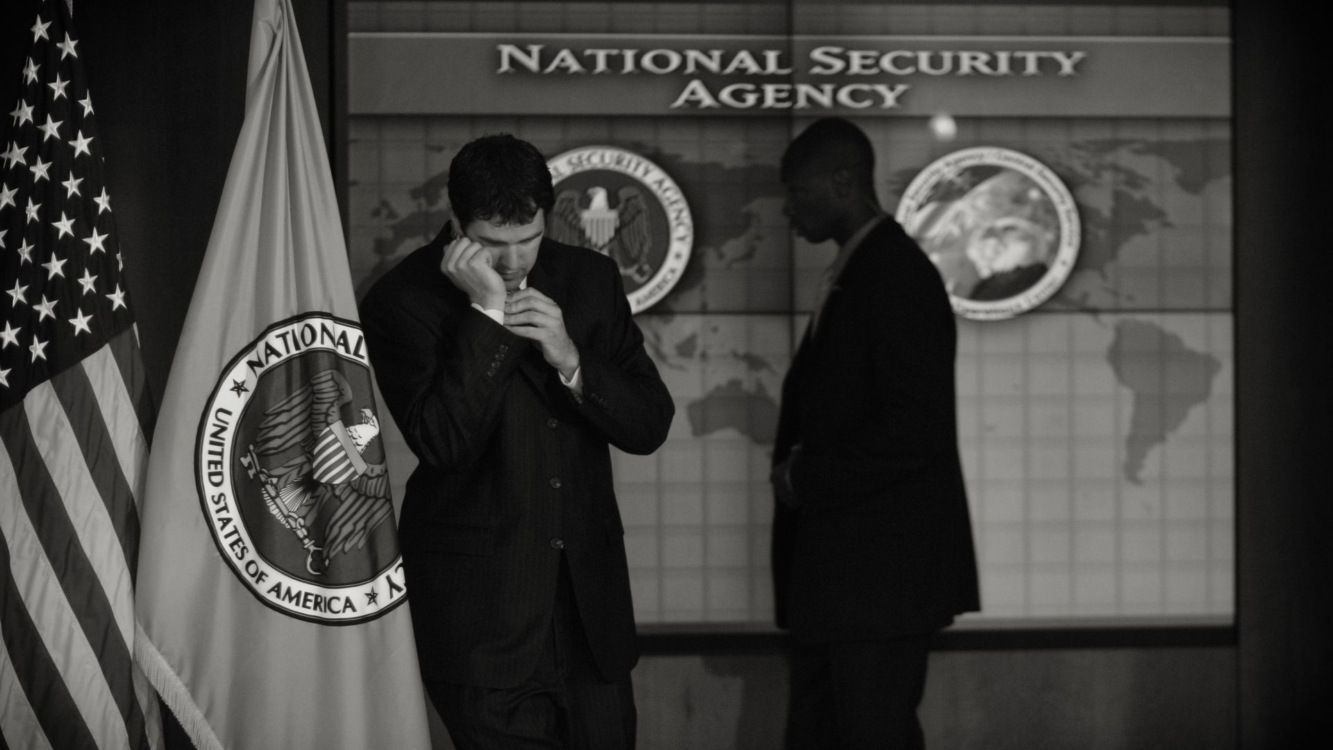 Two men stand below text that reads "National Security Agency"