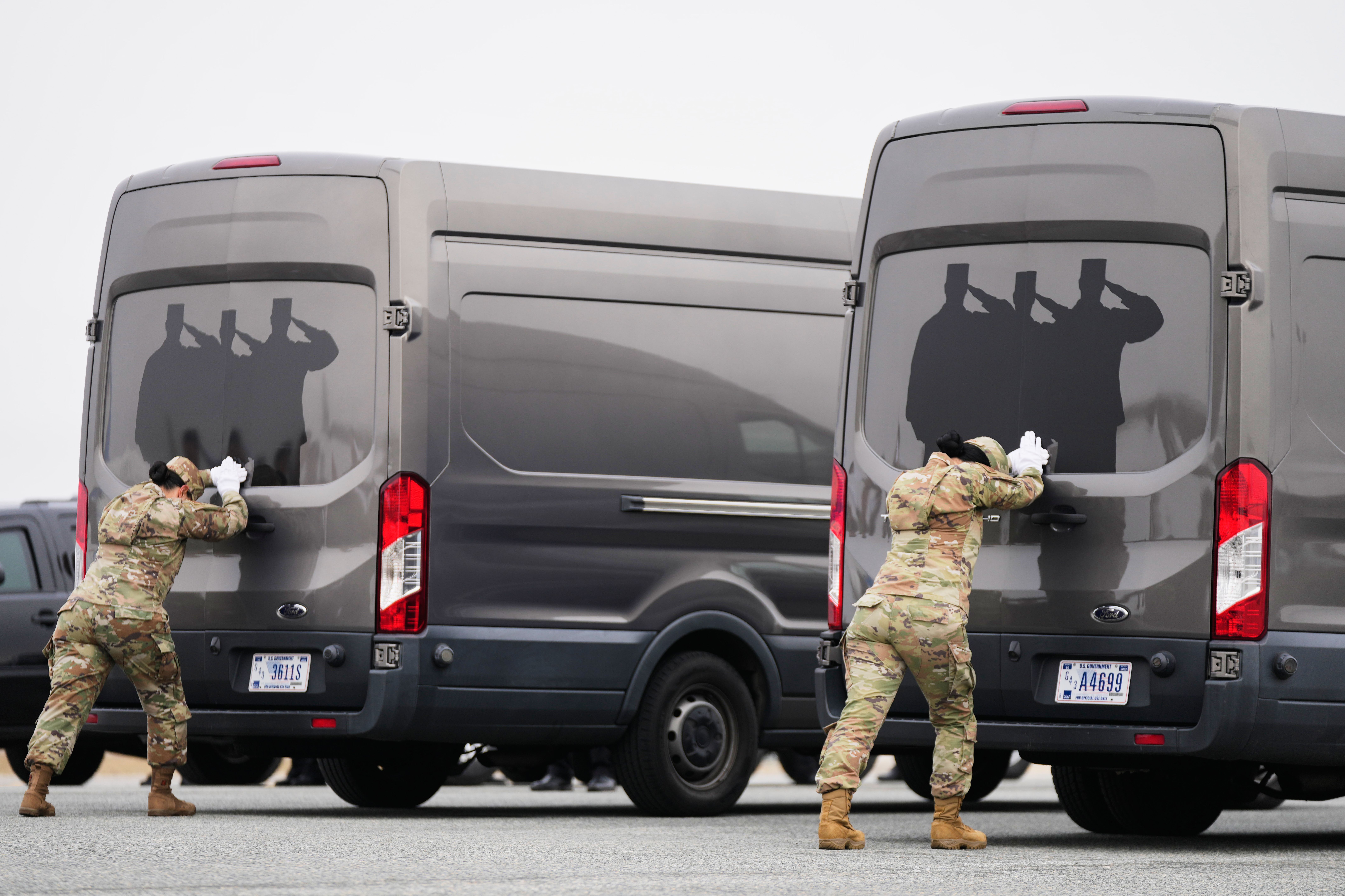 Door attendants U.S. Air Force Master Sgt. Christina Jiminez and Senior Airman Awng Dingrin secure the doors of the transfer vans containing the remains of U.S. Army Reserve soldiers Maj. Jeffrey O'Brien, 45, of Indianola, Iowa, Capt. Cody Khork, 35, of Winter Haven, Florida, Chief Warrant Officer 3