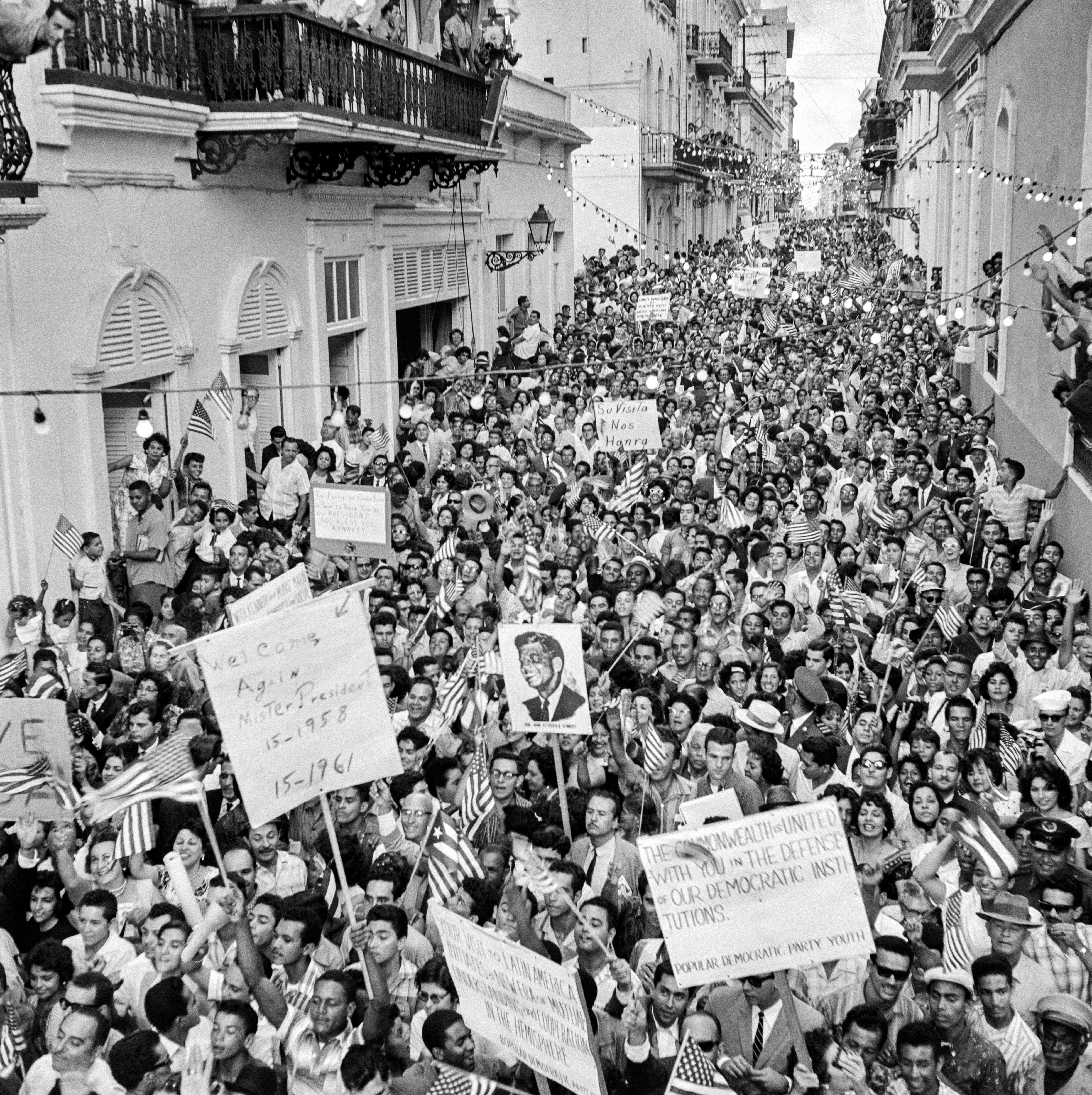 A huge crowd gathers on Calle Fortaleza in San Juan in Puerto Rico to cheer US President John Fitzgerald Kennedy and First Lady Jacqueline Kennedy arriving from San Juan Airport, on December 15, 1961, during the first step of their trip to Latin America. 