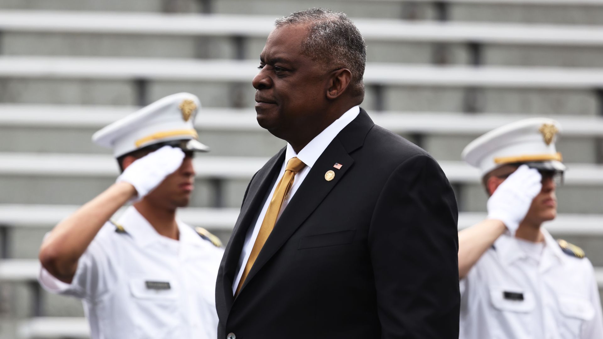 Defense Secretary Lloyd Austin walks bast soldiers who are saluting